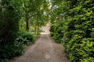 In het hart van Sint-Kornelis-Horebeke, verscholen achter het dorpsplein, ligt dit uitzonderlijk herendomein met bijgebouw op een volledig omwald terrein van meer dan 6.000 m². De voormalige herenhoeve, gebouwd in de eerste helft van de 18de eeuw, is erkend als beschermd erfgoed en straalt een zeldzame historische grandeur uit. Met zijn statige gevelstructuur in vijf traveeën, hoge plafonds, monumentale schouwen en decoratieve schilderingen op doek, ademt deze eigendom authenticiteit en karakter.<br /><br />Bij binnenkomst valt meteen de royale inkomhal op, afgewerkt met marmeren vloeren en geflankeerd door twee elegante salons, elk met een eigen sfeer en historische aankleding. Aansluitend vinden we een ruime woonkamer, een aparte eetkamer en een keuken die uitkijkt op het groene parkdomein. Deze gelijkvloerse ruimtes bieden naast comfort ook talloze mogelijkheden voor wie werk en privé wil combineren of op zoek is naar een veelzijdige invulling. Op de eerste verdieping is er ruimte voor het inrichten van meerdere royale slaapkamers en badkamers. De tussenverdieping en de zolderverdieping bieden bijkomend potentieel voor uitbreiding of creatieve herbestemming.<br /><br />Een troef van deze eigendom is de volledig gerenoveerde bijwoning, die discreet achter het hoofdgebouw ligt. Deze beschikt over een eigen leefruimte, keuken, badkamer en slaapkamer, en wordt momenteel verhuurd. Deze bijkomende woonunit is ideaal als opbrengsteigendom, gastenverblijf of praktijkruimte. Daarnaast is er nog extra uitbreidingspotentieel.<br /><br />Wat dit pand werkelijk uniek maakt, is het perceel zelf: een omwalde tuin van meer dan 6.000 m² die rust, privacy en natuurbeleving garandeert. Het parkdomein vormt een zeldzame groene oase in het centrum van het dorp en versterkt de totaalervaring van het wonen in erfgoed.<br /><br />Deze eigendom is uitermate geschikt voor wie op zoek is naar een ruim familiehuis met ziel, een karaktervol landgoed, combinatie van wonen en professioneel gebruik of een creatieve invulling.<br /><br />Een unieke kans om een stukje Vlaamse geschiedenis nieuw leven in te blazen, op een plek waar tijd lijkt stil te staan, maar mogelijkheden oneindig zijn.