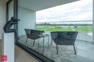 Residentie Hippopolis. Een van de meest gegeerde woonlocaties van Waregem. Lichtrijk hoek-appartement bestaande uit een inkomhall, lichtrijke living, ingerichte open keuken, 2 slaapkamers met elk badkamer, grote terrassen (zonnekant vooraan, zicht op renbaan achteraan). Ganse dag zon (zonwering voorzien). Met mooie materialen afgewerkt. Inclusief 2 private standplaatsen. (Momenteel verhuurd)