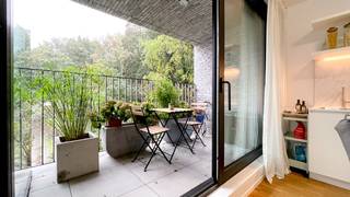 <p>Cet appartement d’environ 63 m² est situé au premier étage de la petite résidence neuve Hof van Leysen, un projet d’angle architectural raffiné conçu par M2 Architecten. La résidence doit son nom à son emplacement unique, à proximité du parc éponyme, qui traverse ce quartier résidentiel élégant comme une artère verte et offre une sensation exceptionnelle de calme et d’espace.</p>
<p>L’appartement se trouve dans la très recherchée Markgravelei, en plein cœur du quartier Markgrave. L’emplacement est particulièrement pratique : à deux pas de la Jan Van Rijswijcklaan, avec un accès direct au Ring et au Singel, et à distance de marche du centre-ville. À proximité immédiate, vous trouverez de nombreux cafés et restaurants conviviaux tels que Domestic, Bunch, The Finch, Cèpes et Café Kamiel, bientôt rejoints par Cobra House.</p>
<p>Conçu par M2 Architecten, l’appartement bénéficie de finitions haut de gamme. Le séjour avec cuisine ouverte dispose d’un parquet continu et donne un accès direct à la terrasse orientée sud-est, d’où vous pourrez profiter en toute tranquillité de la vue sur le parc Hof van Leysen.</p>
<p>La cuisine moderne, blanche et sans poignées, est entièrement équipée avec des appareils encastrés de qualité, comprenant une plaque de cuisson, un lave-vaisselle, un réfrigérateur avec compartiment congélateur et un four combiné. La chambre dispose de placards encastrés et est attenante à la salle de bain, aménagée avec une douche, un lavabo et des toilettes.</p>
<p>De plus, un espace de rangement séparé avec branchement pour machine à laver est prévu. L’appartement est prêt à emménager et extrêmement économe en énergie, avec notamment un chauffage au sol continu. Une cave privative est incluse dans le prix et un local à vélos commun est disponible.</p>