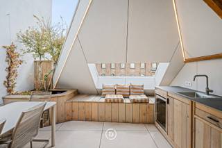 Dit uitzonderlijk gerenoveerd duplex appartement bevindt zich op een unieke historische locatie in het hart van het Patershol. Het appartement combineert hedendaags comfort en hoogwaardige afwerking met een bijzonder woongevoel dankzij het frontale zicht op het water, het terras aan de leefruimte en het ruime dakterras.<br /><br />Gelegen in een kleinschalige residentie met slechts drie entiteiten geniet dit appartement van maximale privacy en het voordeel van geen maandelijkse gemeenschappelijke kosten. De authentieke charme van het Patershol, de gezellige horeca en de nabijheid van het stadscentrum maken dit tot een bijzonder gegeerde locatie.<br /><br />Binnenin staan licht, ruimte en verfijnde afwerking centraal. Grote raampartijen, een patio en een centrale lichtstraat zorgen voor een uitzonderlijk lichtrijk interieur.<br /><br />De inkomhal met ingemaakte kasten en gastentoilet geeft toegang tot de stijlvolle leefruimte met open keuken. De keuken is volledig uitgerust en afgewerkt met een werkblad in kwartsiet natuursteen en hoogwaardige elementen zoals een Quooker kraan. Vanuit de leefruimte geniet u van een prachtig frontaal zicht op het water en heeft u directe toegang tot het terras.<br />Op deze verdieping bevindt zich een slaapkamer met ensuite badkamer, voorzien van een inloopdouche, wastafel en toilet. De badkamer werd afgewerkt met hoogwaardig kraanwerk van Gessi.<br /><br />De architecturale draaitrap leidt naar de bovenverdieping met master bedroom, ingericht met een uitgesproken hotelgevoel. De glazen ensuite badkamer beschikt over een inloopdouche, ligbad en dubbele wastafel. Daarnaast is er een tweede kamer die perfect kan dienen als bureau, kinderkamer of hobbyruimte.<br /><br />De absolute troef van dit appartement is het ruime dakterras met eetruimte en buitenkeuken. Een unieke plek om te genieten van lange zomeravonden, het uitzicht en de charme van historisch Gent.<br /><br />Een uitzonderlijk duplex appartement voor wie op zoek is naar karakter, luxe, privacy en een topligging in het hart van het Patershol.
