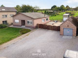 Voor meer info en foto’s, surf naar www.swevers.be – Vrijheerstraat 24 in Sint-Truiden biedt gelijkvloers wonen op een uitzonderlijk ruim perceel van 2.624 m². Deze open bebouwing uit 1968 ligt rustig en landelijk tussen Sint-Truiden en Heers, vlak bij de N3. De woning heeft een bewoonbare oppervlakte van 132 m², onderging al enkele opfrisbeurten maar heeft ruimte om verder naar eigen smaak te moderniseren. Via de centrale inkomhal bereik je de ruime leefruimte van 37 m² met plaats voor een comfortabele zit- en eethoek. Aansluitend bevindt zich de vernieuwde keuken van 11 m². Verder zijn er een badkamer met inloopdouche, een praktische berging en twee volwaardige slaapkamers van 12,60 m² en 14,40 m². Een zolder, bereikbaar via buiten, en een bijgebouw zorgen voor extra opslagruimte. De dubbele garage biedt plaats aan twee wagens. Een absolute troef is de grote, zuidwestelijk georiënteerde tuin. Dankzij de royale oppervlakte zijn er tal van mogelijkheden voor een terras, speelruimte, moestuin of groene ontspanningszones. Ook de ligging is praktisch: scholen bevinden zich op ca. 600 meter, openbaar vervoer op 800 meter, restaurants op 2 km en winkels op ongeveer 4 km. De snelweg (E40) ligt op circa 5,7 km. Een interessante woning voor wie ruimte, rust en gelijkvloers comfort zoekt en graag zelf verder vorm geeft aan zijn toekomstige thuis. Voor meer informatie, bel 011 255 155. Bron bewoonbare oppervlakte: EPC – verslag. Dit pand is onderworpen aan de renovatieverplichting van de Vlaamse overheid voor residentiële gebouwen (behoudens bij sloop binnen 5 jaar na de aankoop). Consulteer voor meer informatie de website van het Vlaams Energie- en Klimaatagentschap via https://www.vlaanderen.be/een-huis-of-appartement-kopen/renovatieverplichting-voor-residentiele-gebouwen.