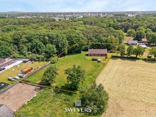 De woning heeft een bewoonbare oppervlakte van 282 m² en werd in 1994 degelijk opgetrokken in betonblokken, wat zorgt voor een stevige en duurzame constructie. Dankzij de praktische indeling en ruime opzet biedt deze eigendom heel wat wooncomfort en flexibiliteit. Via de inkomhal komt u terecht in de lichtrijke leefruimte van 27,80 m², voorzien van grote raampartijen en een gezellige houtkachel. Aansluitend bevindt zich de keuken van 12 m² met zicht op het omliggende groen. Naast de keuken is er een berging die multifunctioneel gebruikt kan worden, bijvoorbeeld als wasplaats, voorraadruimte of bureau. Op het gelijkvloers vindt u verder een badkamer, een afzonderlijk toilet en een slaapkamer van 17 m². Hierdoor is wonen op één niveau perfect mogelijk, al kan deze ruimte ook worden ingevuld als bureau, hobbykamer of logeerruimte. De zolderverdieping omvat drie volwaardige slaapkamers van 11,90 m², 14,84 m² en 30,03 m². Daarnaast zijn er meerdere aansluitende ruimtes die kunnen worden ingericht als dressing of extra bergruimte. De ruime overloop kan bovendien worden gebruikt als bureauhoek, speelruimte of compacte fitnessruimte, afhankelijk van de behoeften. Een belangrijke meerwaarde is de ruime garage van 61,49 m², geschikt voor meerdere voertuigen, maar ook ideaal als werkplaats of hobbyruimte. Aansluitend is er nog een praktische berging voor fietsen, tuinmateriaal en bijkomende opslag. Buiten geniet u van een uitzonderlijk perceel van 4.010 m² met noordwestelijke oriëntatie. De woning ligt volledig in een groene omgeving zonder directe buren, wat zorgt voor een uitzonderlijk gevoel van rust en maximale privacy. Het terrein biedt alle mogelijkheden voor tuin, ontspanning en buitenleven. Qua technieken is de woning uitgerust met een regenwaterput van 16.000 liter met buitenfilter tegen bladeren, wat bijdraagt aan een efficiënt watergebruik. De degelijke bouw en functionele indeling maken dit een solide en veelzijdige woonst. Ondanks de rustige ligging zijn alle nodige voorzieningen vlot bereikbaar: de snelweg ligt op 2,3 km, openbaar vervoer op 900 m, scholen op 3,6 km en winkels en restaurants op korte afstand. Deze eigendom combineert ruimte, privacy en groen wonen op een unieke manier. Voor bijkomende informatie of een bezoek kunt u contact opnemen via 011 255 155. Bron bewoonbare oppervlakte: EPC-rapport.