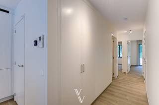 Dit gelijkvloers nieuwbouwappartement van 99 m² (bruto) maakt deel uit van een kleinschalige residentie met slechts 5 appartementen en is gelegen in het centrum van Zandhoven. Het appartement beschikt over 2 slaapkamers, een zuidwestgericht terras van 13,2 m², een privatief tuintje, een ondergrondse autostaanplaats en een private berging.<br /><br />Indeling<br />Via de inkomhal met vestiairekast en apart gastentoilet komt u in de ruime leefruimte van 43,6 m². Dankzij de grote raampartijen geniet de leefruimte van veel natuurlijk licht en heeft u rechtstreeks toegang tot het terras en de tuin.<br /><br />De open keuken is volledig ingericht en voorzien van:<br />- keramisch werkblad<br />- Quooker-kraan<br />- inductiekookplaat<br />- combi-oven<br />- koelkast met aparte diepvriezer<br />- ruim kookeiland<br />- veel opbergkasten<br /><br />De badkamer is uitgerust met een inloopdouche, een dubbel lavabomeubel, een badkamerkast en een handdoekdroger.<br /><br />Verder beschikt het appartement over twee slaapkamers en een afzonderlijke berging met aansluitingen voor wasmachine en droogkast, de warmtepomp en het ventilatiesysteem.<br /><br />Afwerking en technieken<br />Het volledige appartement is afgewerkt met een keramische parketvloer en wordt volledig geschilderd opgeleverd.<br /><br />Daarnaast zijn inbegrepen:<br />- alle verlichtingsarmaturen<br />- Louverdrape lamelgordijnen in de leefruimte<br />- verduisterende raamdecoratie in de slaapkamers<br />- vliegenramen op maat<br /><br />Voor verwarming en sanitair warm water wordt gebruikgemaakt van een Daikin warmtepomp in combinatie met vloerverwarming. Met dit type verwarmingssysteem kan de vloer ook gekoeld worden, wat het enorm aangenaam leven maakt bij warme zomerdagen. Het appartement beschikt bovendien over 4 privatieve zonnepanelen, Niko Home Control-domotica en behaalt een E-peil van E13, wat resulteert in een zeer energiezuinige woning.<br /><br />Extra<br />- Ondergrondse autostaanplaats<br />- Private berging <br />- Zuidwestgericht terras van 13,2 m²<br />- Privatief tuintje van ca. 17 m²<br />- Bushalte, winkels, horeca en andere voorzieningen op wandelafstand.<br /><br />*3m HWB<br />*Plaatsbeschrijving<br />*Beschikbaar vanaf 15/08/2026<br />* EPB in opmaak - nieuwbouw