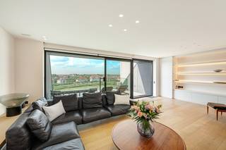 <p>Appartement exceptionnel situé dans la résidence et l’hôtel renommés « La Réserve – La Rive », bénéficiant d’une vue frontale sur le Zegemeer. Ce bien a été réalisé avec des matériaux d’un très haut niveau de finition. Possibilité d’acquérir un double garage dans la résidence.</p>
<p>L’appartement comprend un vaste hall d’entrée avec plusieurs armoires vestiaires, un grand local de rangement avec raccordement pour machine à laver et sèche-linge, l’installation de chauffage et un espace de stockage, ainsi qu’un toilette invités. Le spacieux séjour, offrant une largeur de façade de 7,50 m, donne accès à une superbe terrasse avec vue frontale sur le Zegemeer. La cuisine ouverte moderne avec îlot central est entièrement équipée et donne accès à une large terrasse ensoleillée avec vue sur le Zegemeer.</p>
<p>L’appartement dispose de quatre chambres et de trois salles de bains. La chambre principale comprend un dressing attenant et une salle de bains spacieuse. Les deux autres chambres sont aménagées avec un lit double, un bureau et des placards intégrés. À l’étage, se trouvent également une salle de douche séparée et un espace de vie supplémentaire.</p>
<p>Une cave privative et un local à vélos commun pouvant accueillir plusieurs vélos sont inclus. Le propriétaire dispose d’un double garage avec porte sectionnelle dans l’immeuble.</p>