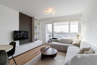 <p><span>Gerenoveerd appartement (77 m²) in Antwerpen met 2 slaapkamers en 2 terrassen met zicht op het Rivierenhof.</span></p><p><span> </span></p><p><span>Recht tegenover het Rivierenhof, bevindt zich op de vijfde verdieping van een verzorgd gebouw dit lichtrijke hoekappartement. Dankzij deze topligging geniet je van een uitstekende bereikbaarheid met tram, bus, velo en wagen, terwijl het uitgestrekte groen van het Rivierenhof letterlijk aan je overkant ligt. Met de toekomstige overkapping van de Ring gaat het een naadloze overgang worden naar een nog groenere omgeving.</span></p><p><span> </span></p><p><span>Het appartement maakt deel uit van een verzorgd en goed onderhouden gebouw waarvan het dak conform geïsoleerd werd. Dit hoekappartement werd in 2023 volledig en met bijzonder veel oog voor detail gerenoveerd, waarbij gekozen werd voor kwalitatieve en duurzame materialen. Dankzij de talrijke ingemaakte kasten werd de beschikbare ruimte optimaal benut, wat zorgt voor een strak en functioneel geheel. De elektriciteit is conform, de ramen zijn voorzien van dubbele beglazing en met een gunstige EPC-score B ben je verzekerd van energiezuinig wooncomfort.</span></p><p><span> </span></p><p><span>Een hoekappartement betekent maximale lichtinval én twee terrassen. Je beschikt over een oost-georiënteerd terras van 4 m² en een ruim zuid-terras van 11 m², met zicht op het Rivierenhof. Binnenkomen doe je in de inkomhal met ingemaakte vestiairekast, waarbij aansluiting voorzien werd voor een wasmachine. De eerste slaapkamer (13 m²) biedt een comfortabele oppervlakte en bevindt zich tegenover de moderne badkamer (5 m²), uitgerust met een lavabomeubel en inloopdouche. Het toilet is apart voorzien. De tweede slaapkamer (7 m²) is perfect inzetbaar als dressing, bureau of kinderkamer — een flexibele ruimte die je naar eigen noden kan invullen. De lichtrijke leefruimte (29 m²) vormt het hart van het appartement. Hier is de op maat gemaakte keuken in donker houtfineer een echte eyecatcher. Ze combineert een stijlvolle uitstraling met hedendaags comfort en maakt koken en tafelen tot een plezierige ervaring. Tot slot is er achteraan het gebouw een gratis bewonersparking waar je gebruik van kan maken en een gemeenschappelijke fietsenstalling beschikbaar.</span></p><p><span>Ben je op zoek naar een instapklaar appartement? Mis deze kans niet! Bewoonbare opp. 77 m² ref.: bruto vloeropp. Voor meer info of een gratis schatting surf naar </span><span><span>www.hansimmo.be</span></span></p><p><span> </span></p>