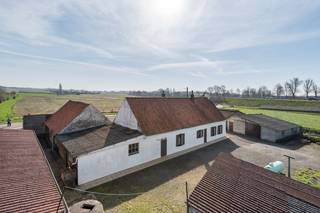 In een rustige, doodlopende straat bevindt zich dit charmante landelijke eigendom, een unieke opportuniteit voor wie houdt van rust, ruimte en het buitenleven. Het perceel van 5.504 m² omvat een te renoveren of eventueel te herbouwen landhuis, diverse bijgebouwen en een ruime weide.<br />De woning beschikt momenteel over een woonkamer, leefkeuken, twee slaapkamers, een badkamer en een berging. Ze vormt de ideale basis voor een grondige renovatie of de realisatie van een nieuw woonproject, afhankelijk van de geldende stedenbouwkundige voorschriften.<br />Op het domein bevinden zich bovendien verschillende bijgebouwen, waaronder twee ruime loodsen, een voormalige koestal en een hangar. Deze bieden tal van mogelijkheden voor opslag, een atelier, hobbyactiviteiten, dierenhouderij of andere professionele of recreatieve doeleinden.<br />Achter één van de loodsen ligt een uitgestrekte weide, waardoor het eigendom bijzonder geschikt is voor het houden van paarden of andere dieren. Daarnaast bestaat de mogelijkheid om twee extra weides aan de overzijde van de straat aan te kopen, goed voor een bijkomende oppervlakte van 9.320 m². <br />Dankzij de landelijke ligging, de veelzijdige bijgebouwen en de ruime percelen is dit eigendom uitermate geschikt voor dierenliefhebbers, paardenhouders, natuurliefhebbers, mensen met een landelijke hobby of kleinschalige landbouwactiviteiten, evenals voor wie op zoek is naar extra opslag- of werkruimte.<br /><br />Een eigendom boordevol potentieel, waar karakter, ruimte en een prachtige groene omgeving samenkomen.<br /><br />
