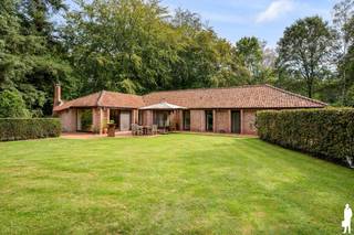 <p><strong>Karaktervolle gelijkvloerse villa op ca. 2.000 m² in zeer rustige, gegeerde en autoluwe wijk Dennendael en dichtbij het natuurgebied</strong></p>
<p>In de <strong>residentiële en bijzonder gegeerde wijk Dennendael</strong> bevindt zich deze karaktervolle gelijkvloerse villa op een royaal perceel van circa <strong>2.000 m²</strong>. De brede architectuur, royale leefruimtes en grote raampartijen creëren een aangenaam gevoel van ruimte en licht, terwijl de volwassen groene omkadering zorgt voor rust en privacy.<br />Met <strong>4 slaapkamers, 2 badkamers, een ruime master suite, dubbele inpandige garage en aangelegde tuin</strong> biedt de woning bovendien een volledig gelijkvloers woonprogramma.</p>
<p><strong>Gelijkvloerse verdieping<br /></strong>- Lichtrijke <strong>inkomhal</strong> met mooie doorkijken naar de woonvertrekken<br />- Gastentoilet<br />- Royale <strong>woon- en eetkamer</strong> met grote raampartijen en zicht op de tuin<br />- Sfeervolle zithoek met <strong>houthaard</strong> en karaktervolle houten balkenstructuur<br />- Groot schuifraam met rechtstreekse toegang tot terras en tuin<br />- Afzonderlijke keuken met <strong>granieten werkblad</strong>, ontbijthoek<br />- Ook vanuit de keuken rechtstreekse toegang tot de tuin<br />- <strong>4 volwaardige slaapkamers </strong>waarvan 1<strong> </strong>master bedroom met ruime <strong>dressing met maatkasten</strong> en ensuite badkamer met <strong>ligbad, inloopdouche en dubbel lavabomeubel<br /></strong>- Tweede badkamer met <strong>douche, lavabo en toilet<br /></strong>- Praktische wasruimte met uitgietbak en deur naar de tuin<br />- Natuurstenen vloer in de leefruimtes en parket in 3 slaapkamers<br />- <strong>Volledige vloerverwarming</strong></p>
<p><strong>Kelder en zolder<br /></strong>- Praktische kelderruimte, ideaal als voorraadruimte met plaats voor extra koelkast en diepvriezer<br />- Overige gedeelte voorzien van kruipruimte<br />- B<strong>ergzolder</strong>, toegankelijk via de garage</p>
<p><strong>Garage en berging<br /></strong>- <strong>Dubbele inpandige garage</strong> met sectionaalpoort<br />- Twee bergingen, waarvan één met toegang naar buiten</p>
<p><strong>Tuin en buitenruimte<br /></strong>- Royaal perceel <strong><br /></strong>- <strong>Aangelegde en zonnige tuin</strong> omgeven door volwassen groen<br />- Veel <strong>rust en privacy<br /></strong>- Ruim terras aansluitend op leefruimte en keuken<br />- Afzonderlijke <strong>overdekte zithoek met openhaard<br /></strong>- Buitenverlichting en meerdere waterpunten<br />- Ruime oprit met parkeergelegenheid voor meerdere wagens</p>
<p><strong>Bijzonderheden<br /></strong>- Verkeersluwe straat met uitsluitend bewonersverkeer in een rustige buurt <br />- <strong>Gegeerde residentiële ligging in Dennendael<br /></strong>- Volledig <strong>gelijkvloers woonprogramma<br /></strong>- <strong>4 slaapkamers en 2 badkamers </strong>waarvan 1 master suite met dressing en ensuite badkamer<br />- Grote glaspartijen en sterke verbinding met de tuin<br />- <strong>Dubbele inpandige garage<br /></strong>- Volledige vloerverwarming op aardgas<br />- Recente hoogrendementsketel<br />- Houten ramen met dubbele beglazing en vliegenramen<br />- Geïsoleerd dak<br />- Natuurgebied op 150 meter</p>
<p><strong>Ligging<br /></strong>Gelegen <strong>in Heide</strong>, midden in de residentiële wijk <strong>Dennendael</strong>. Ruime percelen, volwassen bomen en de nabijheid van het <strong>militair domein en uitgestrekte groenzones</strong> zorgen voor een bijzonder rustige en groene woonomgeving. Het centrum van Heide en de dagelijkse voorzieningen zoals scholen, winkels en station zijn zeer dichtbij.</p>
<p><strong>Een karaktervolle gelijkvloerse villa waar royale woonvolumes, 4 slaapkamers en een prachtig groen perceel samenkomen op een discrete en gegeerde locatie in Dennendael.</strong></p>
<p>Bewoonbare opp. 209 (exclusief garage 35m) m² ref.: bruto vloeropp. EPC-certificaat.</p>
<p></p>