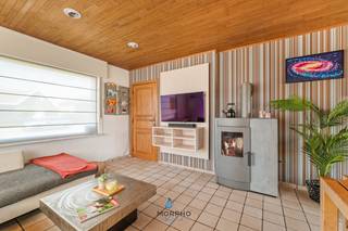 Bent u op zoek naar een ruime gezinswoning waar comfort, functionaliteit en veelzijdigheid samenkomen? Dan is deze verzorgde woning beslist een bezoek waard. Gelegen op een perceel van maar liefst <strong>1.107 m² </strong>biedt deze eigendom een doordachte indeling, tal van multifunctionele ruimtes én een <strong>gunstig EPC C</strong>, waardoor<strong> geen renovatieverplichting</strong> van toepassing is.<br />Bij het binnenkomen wordt u verwelkomd in een lichtrijke leefruimte waar de gezellige pelletkachel meteen voor een warme sfeer zorgt. De eetplaats sluit naadloos aan op de woonkamer en vormt samen met de volledig uitgeruste keuken het hart van de woning. Aansluitend bereikt u het terras en de zonnige tuin, waar u in alle rust kunt genieten van het buitenleven.<br /><strong>Het gelijkvloers</strong> beschikt bovendien over een ruime slaapkamer, een praktische badkamer, een apart gastentoilet, een inpandige garage met aansluitende berging/wasplaats en biedt de mogelijkheid om volledig gelijkvloers te wonen.<br /><strong>Op de voute</strong> bevindt zich een afzonderlijke kamer die momenteel is ingericht als fitnessruimte, maar eveneens perfect kan dienen als bureau, hobbyruimte of extra berging.<br /><strong>De eerste verdieping</strong> beschikt over drie volwaardige slaapkamers, een aparte logeerkamer en de indrukwekkende familiekamer. Deze unieke leefruimte vormt zonder twijfel het pronkstuk van de woning. Dankzij de open nok, de twee Velux-balkonvensters, de gezellige bar en de mezzanine geniet deze ruimte van een uitzonderlijk gevoel van licht en openheid. Een ideale plek om te ontspannen, gasten te ontvangen of volledig naar eigen wens in te richten als speelkamer, thuisbioscoop, hobbyruimte of stijlvolle thuiswerkplek.<br /><strong>Ook buiten is het heerlijk vertoeven</strong>. De zonnige tuin biedt alle ruimte om te ontspannen, te spelen en te genieten van het buitenleven. De ruime oprit biedt parkeergelegenheid voor meerdere wagens.<br />Een extra troef is het bestaande bijgebouw van ca. 60 m². Hiervoor werd reeds een omgevingsvergunning afgeleverd voor afbraak en nieuwbouw. De toekomstige eigenaar beschikt hierdoor over een vergund project voor de realisatie van een nieuw multifunctioneel bijgebouw, een interessante meerwaarde voor wie extra ruimte wenst te creëren.<br /><strong>Troeven</strong>
<ul>
<li>Perceel van 1.107 m²</li>
<li>EPC C – geen renovatieverplichting</li>
<li>Mogelijkheid tot gelijkvloers wonen</li>
<li>3 volwaardige slaapkamers</li>
<li>Aparte logeerkamer</li>
<li>Afzonderlijke fitnessruimte op de voute</li>
<li>Indrukwekkende familiekamer met open nok, bar, mezzanine en twee Velux-balkonvensters</li>
<li>Gezellige leefruimte met houtkachel</li>
<li>Volledig uitgeruste keuken</li>
<li>Inpandige garage met berging/wasplaats</li>
<li>Ruime oprit</li>
<li>Vergund project voor een nieuw multifunctioneel bijgebouw</li>
<li>Zonnige tuin op een perceel van 1.107 m²</li>
</ul>
<strong>Interesse?</strong><br />Ontdek zelf de ruimte, de warme sfeer en de vele mogelijkheden die deze woning te bieden heeft. Contacteer ons vandaag nog voor een bezoek.
