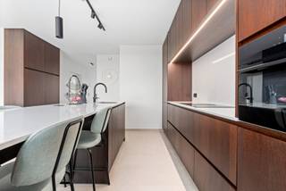 Op een uitstekende ligging, op een boogscheut van het bruisende centrum van Middelkerke, bevindt zich deze exclusieve residentie van amper vijf luxueuze appartementen. Een kleinschalig nieuwbouwproject uit 2025 waar rust, comfort, energiezuinigheid en een hoogwaardige afwerking centraal staan. We bieden u vandaag de unieke mogelijkheid om één van deze exclusieve appartementen te verwerven. <br /><br />De ligging is bijzonder aangenaam: op amper 100 meter van het Normandpark geniet je van een groene omgeving en rustige wandelingen, terwijl het strand, het nieuwe casino, gezellige horeca en winkels op slechts een tiental minuten wandelen bereikbaar zijn. Ook het openbaar vervoer bevindt zich vlakbij.<br /><br />Het appartement zelf biedt maar liefst 124 m² aan hoogwaardig wooncomfort, verdeeld over twee volwaardige verdiepingen. De leefruimtes werden ontworpen met oog voor licht, ruimte en beleving.<br /><br />Vooraan bevindt zich de indrukwekkende leefkeuken, een echte eyecatcher van het appartement. De keuken is uitgerust met een groot kookeiland en afgewerkt met witte natuursteen en elegante zwarte accenten. Een heerlijke plek om uitgebreid te koken, vrienden te ontvangen of gezellig samen te genieten. Vanuit de keuken stap je rechtstreeks het eerste terras van 10 m² op, waar je geniet van een aangenaam en open uitzicht.<br /><br />Aan de andere zijde van de leefruimte bevinden zich de stijlvolle zithoek en een praktische bureauruimte. Hier geniet je van een aangenaam terras van 5 m², perfect georiënteerd om in alle rust van de avondzon te genieten. Verder is er op deze verdieping nog een handige bergruimte en een afzonderlijk toilet.<br /><br />De bovenverdieping biedt plaats aan drie volwaardige slaapkamers. De master bedroom beschikt bovendien over een eigen dressing en biedt een aangename, rustige slaapomgeving. De moderne badkamer vormt een stijlvolle aanvulling op het geheel en is uitgerust met een prachtige inloopdouche.<br /><br />Ook technisch is dit appartement volledig mee met zijn tijd. De residentie wordt voorzien van warmtepompen, vloerverwarming, zonnepanelen en ventilatie type D. In combinatie met de kwalitatieve en duurzame materialen staat dit garant voor een bijzonder comfortabel, energiezuinig en toekomstgericht woonconcept.<br /><br />Voor wie extra comfort wenst, bestaat de mogelijkheid om een carport met berging aan te kopen voor € 35.000.<br /><br />Een uitzonderlijk appartement voor wie op zoek is naar ruimte, luxe, energiezuinigheid en een uitstekende ligging aan de Belgische kust. De verkoop gebeurt onder het btw-stelsel. De plannen zijn beschikbaar en kunnen via onze website worden geraadpleegd.<br /><br />De aanwezige meubelen kunnen eventueel mee worden overgenomen.<br /><br />Een unieke kans om te wonen in een kleinschalige en exclusieve residentie, vlak bij alles wat Middelkerke te bieden heeft.
