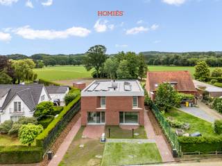 Deze prachtige halfopen nieuwbouwwoning in Lubbeek combineert hedendaags wooncomfort met een rustige, groene omgeving. De woning wordt opgeleverd in juli 2026 en werd ontworpen met oog voor ruimte, licht en energiezuinigheid. Bij het binnenkomen wordt u verwelkomd in een ruime en lichtrijke leefruimte met open keuken. Dankzij de grote raampartijen geniet u hier van een aangenaam zicht op de tuin, een patio en een overvloed aan natuurlijk licht. Verder beschikt het gelijkvloers over een praktische berging en een gastentoilet. Op de verdieping bevinden zich drie volwaardige slaapkamers (waarvan 1 met volledig ingerichte dressing) en een comfortabele badkamer. Buiten geniet u van een uitzonderlijk ruim perceel van ongeveer 30 are met een prachtige zuidgerichte tuin en bos. Het achterste gedeelte is gemeenschappelijk en wordt onderhouden door de verhuurder. Bovendien beschikt elke woning over een eigen tuinhuis met elektriciteitsaansluiting. De woning is uitgerust met zonnepanelen, vloerverwarming, een lucht-waterwarmtepomp, ventilatiesysteem type D, een regenwaterput en een laadpaal voor elektrische voertuigen. Naast de huurprijs van € 2.090 per maand wordt een vaste kost van € 100 per maand voorzien voor gemeenschappelijke kosten. Het dagelijkse en reguliere onderhoud van de tuin tot aan de tuinhuisjes blijft de verantwoordelijkheid van de huurder. Wenst u graag een bezoek of extra informatie? info@homies.be