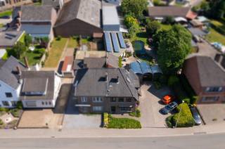 In Bilzen bevindt zich deze uitzonderlijk ruime woning met een bewoonbare oppervlakte van ca. 300 m², gelegen op een perceel van ca. 14 are. De eigendom ligt op wandelafstand van het centrum, winkels, scholen en horeca, met een vlotte verbinding naar omliggende gemeenten en invalswegen. Rustig wonen en toch centraal: hier geniet u van het beste van beide werelden.<br /><br />De woning onderscheidt zich door haar doordachte indeling en royale volumes. Ze beschikt over zeven volwaardige slaapkamers, waarvan vijf kamers zijn uitgerust met een eigen badkamer en toilet. Dit zorgt voor een bijzonder hoog comfortniveau en veel privacy binnen het gezin. De twee overige slaapkamers kunnen perfect dienst doen als kinderkamer, bureau, hobbyruimte of extra logeerkamer.<br /><br />Dankzij deze indeling is de woning bovendien uitermate geschikt voor vrije beroepers zoals artsen, therapeuten, consultants of andere zelfstandigen die wonen en werken willen combineren. De aanwezigheid van meerdere kamers met privatief sanitair biedt tal van mogelijkheden voor praktijk- of consultatieruimtes, met behoud van een duidelijke scheiding tussen privé en professioneel gebruik.<br /><br />De leefruimtes zijn ruim en lichtrijk opgevat, met voldoende plaats voor een comfortabele zithoek en een grote eettafel. Daarnaast beschikt de woning over een aparte wellnessruimte met sauna en jacuzzi, wat een extra dimensie van ontspanning toevoegt aan het geheel.<br />Ook buiten overtuigt deze eigendom. De ruime tuin op het perceel van ca. 14 are vormt een aangename en groene omgeving met een mooie zwemvijver, waar u in alle rust kan genieten tijdens de zomermaanden. Op het perceel zijn bovendien 4 à 5 autostaanplaatsen voorzien, wat zowel voor een groot gezin als voor een professionele activiteit bijzonder praktisch is.<br /><br />Op energetisch vlak is de woning uitgerust met 36 zonnepanelen, wat bijdraagt aan een lagere energiefactuur en een toekomstgerichte investering vormt.<br /><br />Het is een veelzijdige en ruime eigendom, perfect voor een groot gezi