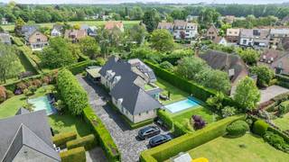 Deze exclusieve, vrijstaande villa in landelijke stijl in Wemmel straalt pure klasse uit. Met een royale bewoonbare oppervlakte van 526 m² en een superieure afwerkingsgraad geniet u hier van uitzonderlijk wooncomfort. De zandkleurige gevel combineert harmonieus met charmante dakkapellen en een monumentale glaspartij bij de inkom. De woning is energie-efficiënt uitgerust met zonnepanelen en een hoogwaardig alarmsysteem.De villa ligt op een discreet perceel, volledig aan het oog onttrokken via een lange privé-inrit. Dit garandeert honderd procent privacy en sereniteit, terwijl scholen, openbaar vervoer en de Brusselse Ring (R0) vlakbij zijn.Binnen opent de inkomhal in een spectaculaire vide met een marmeren trappartij. De centrale leefruimte ademt licht dankzij kamerhoge schuiframen naar de tuin. De living beschikt over een formele eethoek, een zithoek met maatwerkkasten en een sfeervol tweede salon met gashaard. Daarnaast is er een onafhankelijke praktijk- of kantoorruimte op het gelijkvloers.De high-end leefkeuken met werkeiland en premium Miele-apparatuur sluit naadloos aan op het terras. Op de verdieping biedt de mezzanine toegang tot vier grote slaapkamers met ingebouwde kasten en drie stijlvolle, moderne badkamers. De master suite beschikt over een eigen dakterras.De prachtig aangelegde tuin is omzoomd door hoge hagen en beschikt over een strak buitenzwembad met hardhouten zonneterrassen. Aan de voorzijde biedt de oprit plaats voor een tal van wagens.Bestuursmaatregelen in het maatregelenregister: nee