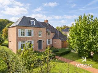 <h3>Statige, recente villa met uitzonderlijke parktuin en tijdloze klasse<span></span></h3>
<p>Deze bijzonder stijlvolle en perfect onderhouden villa combineert een statige architectuur met een verrassend warme woonbeleving op een 25 autominuten van zowel Eindhoven (NL) als Antwerpen. De fraaie architectuur, hoge raampartijen, karaktervolle dakvormen en elegante luiken zorgen voor een tijdloze uitstraling, terwijl binnen vooral ruimte, licht en comfort centraal staan.</p>
<p>Bij het betreden van de woning komt u binnen in een fraaie inkomhal met gastentoilet. Aansluitend bevindt zich een afzonderlijke bureauruimte, ideaal voor thuiswerk. De woonkamer en eetkamer sluiten mooi op elkaar aan en genieten dankzij de grote raampartijen van prachtige zichten op de tuin.</p>
<p>De volledig geïnstalleerde keuken vormt een aangename en functionele leefruimte en beschikt over een praktische naastgelegen berging/wasplaats. Ook de inpandige garage draagt bij aan het dagelijkse comfort en maakt deze woning bijzonder praktisch in gebruik.</p>
<p>Op de verdieping bevindt zich de royale hoofdslaapkamer, waar u ontwaakt met een werkelijk sprookjesachtig uitzicht over de tuin. Deze master suite beschikt over een eigen dressing en een ruime, luxueus uitgewerkte badkamer. Verder bevinden zich op deze verdieping nog drie volwaardige slaapkamers, een tweede badkamer en een afzonderlijk nachttoilet.</p>
<p>De zolderverdieping biedt bijkomende mogelijkheden en kan verder worden ingericht als extra slaapkamer, werkruimte, hobbykamer of polyvalente ruimte.</p>
<h3>Een tuin die u moet beleven</h3>
<p>Ook buiten weet deze villa bijzonder te overtuigen. De volledig omheinde tuin is met veel gevoel voor groen, privacy en beleving aangelegd en vormt zonder twijfel één van de absolute troeven van de eigendom.</p>
<p>Direct aan de woning bevindt zich een heerlijk zonneterras, ideaal voor lange zomerse lunches en diners. Verderop in de tuin ligt een tweede, bijzonder sfeervol terras onder de platanen, een plek waar u op warme dagen in alle rust van de schaduw kunt genieten.</p>
<p>Achteraan op het perceel bevindt zich bovendien een eigen groentetuin met plantenkas, aangevuld met een mooie en praktische tuinberging. Volwassen beplanting, sierlijke hagen, bloeiende hortensia’s en lavendel, open gazons en verschillende zichtlijnen zorgen ervoor dat de tuin telkens opnieuw weet te verrassen.</p>
<p>De woning is recent, perfect onderhouden en volledig instapklaar : alles is aanwezig om onmiddellijk te genieten.</p>
<p>Kortom: een uitzonderlijk complete villa waar uitstraling, comfort, praktische bruikbaarheid en een unieke buitenbeleving op een bijzonder fraaie manier samenkomen. Een eigendom voor wie op zoek is naar rust, privacy, ruimte en kwaliteit — zonder in te boeten op wooncomfort.</p>