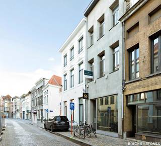 Op een centrale locatie in Mechelen, vlak bij de historische binnenstad en diverse winkels en horecazaken, bevindt zich dit veelzijdige pand in de vernieuwde Sint-Katelijnestraat. De Sint-Romboutskathedraal, de Grote Markt en winkelstraat De Bruul liggen op korte wandelafstand.<br /><br />Vandaag is het eigendom ingedeeld als handelspand met woonst, maar het kan zonder veel moeite worden omgevormd tot een ruime ééngezinswoning.<br /><br />Het gelijkvloers bestaat uit een commerciële ruimte van ca. 35 m², momenteel vrij van huur en afgewerkt met kwalitatief maatwerk. Dankzij de praktische indeling en zichtbare ligging is deze ruimte geschikt voor uiteenlopende activiteiten zoals een kantoor, praktijkruimte of detailhandel.<br /><br />Het bovenliggende duplexappartement met twee slaapkamers is bereikbaar via een aparte inkom en is instapklaar. Op de eerste verdieping bevindt zich een lichtrijke leefruimte met gashaard en een warme parketvloer. De open designkeuken met kookeiland is uitgerust met kwalitatieve BOSCH-toestellen, waaronder een gasfornuis, combi-oven, koelkast, vriezer en vaatwasser.<br /><br />De tussenverdiepingen werden efficiënt benut met extra bergruimte en een afzonderlijk gastentoilet met handenwasser.<br /><br />Op de tweede verdieping vinden we een tweede slaapkamer, die momenteel dienstdoet als bureauruimte, met aansluitend een moderne badkamer voorzien van zowel een douche als een bad en een enkele lavabo met meubel.<br /><br />De ruime master bedroom van ca. 28 m² bevindt zich op de bovenste verdieping en geniet van veel natuurlijk licht dankzij de grote Veluxramen.<br /><br />Het gebouw werd volledig gerenoveerd in 2010 en verkeert in instapklare staat. Daarnaast beschikt het over airconditioning en een alarmsysteem. Een eigendom met tal van mogelijkheden op een uitstekende locatie.