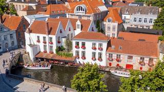 LUXUEUS DAKAPPARTEMENT met authentieke charme en UNIEK UITZICHT.
Dit uitzonderlijk afgewerkte dakappartement met een totale bruto oppervlakte van 189 m2  combineert authentieke elementen, zoals originele balken, met hedendaagse architectuur en hoogwaardig comfort. Het beschikt over 2 slaapkamers en een uniek terras/balkon met prachtig uitzicht op de OLV-kerk.
Het appartement omvat een inkomhal met vestiaire en toilet, een volledig uitgeruste keuken met hoogwaardige Miele-toestellen, een sfeervolle zithoek en een unieke eetplaats met leeshoek/bibliotheek. Beide slaapkamers beschikken over maatkasten. Verder is er een luxueuze badkamer, afgewerkt met mortex, Vola-kraanwerk en travertin, en een praktische berging.
De hoogwaardige afwerking omvat eiken parket, Dark-verlichting, vloerverwarming, airco, warmtepomp, domotica, videoparlofonie, blokkaderdeuren en nieuw schrijnwerk met dubbel glas. Verder zijn er een lift, private berging en gemeenschappelijke fietsenberging.
Er is tevens mogelijkheid tot aankoop van één of meerdere autostaanplaatsen in het gebouw.
Kopers hebben inspraak in de keuze van de afwerking binnen een ruim voorzien budget.
Een unieke combinatie van karakter, hedendaagse luxe en een prachtig uitzicht, midden in het historische Brugge.