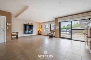 Voor meer info en foto’s, surf naar www.swevers.be – Dit instapklare gelijkvloerse appartement in het centrum van Zolder combineert een ruime indeling met aangenaam wooncomfort. Met een bewoonbare oppervlakte van 120 m², drie slaapkamers en een privatieve tuin rondom is dit een ideale woning voor wie comfortabel en gelijkvloers wil wonen. Het appartement maakt deel uit van een verzorgd gebouw uit 2007 en beschikt bovendien over een ondergrondse autostaanplaats en een kelderberging. Via de inkomhal bereikt u de ruime leefruimte van bijna 52 m², waar woonkamer en eetkamer naadloos in elkaar overvloeien. Dankzij de royale oppervlakte geniet u hier van alle vrijheid om een gezellige zithoek en een volwaardige eethoek in te richten. Aansluitend bevindt zich de praktische keuken met voldoende werk- en opbergruimte. De nachthal geeft toegang tot drie slaapkamers van respectievelijk 13,26 m², 9,51 m² en 9,07 m². Deze ruimtes zijn perfect inzetbaar als slaapkamer, bureau, hobbykamer of logeerkamer. De badkamer is uitgerust met zowel een bad als een douche. Daarnaast is er een aparte toiletruimte en een handige berging. Buiten geniet u van een tuin rondom het appartement, met een terras aan de voorzijde en een overdekt terras van 9,61 m² aan de achterzijde. De zuidwestgerichte achtertuin biedt volop zon in de namiddag en avond en vormt een aangename plek om tot rust te komen. Extra troeven zijn de zonnepanelen, rolluiken, parlofoon, lift en de vlotte verbinding tussen de ondergrondse parking en het appartement. Scholen, winkels, restaurants, openbaar vervoer en ontspanningsmogelijkheden bevinden zich op wandel- of korte rijafstand. Ook de snelwegen zijn snel bereikbaar. Voor meer informatie, bel 011 255 155. Bron bewoonbare oppervlakte: EPC – verslag.