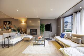 Deze smaakvolle bel-étagewoning is uitstekend gelegen op slechts 500 meter van de zeedijk van Heist en Duinbergen en vormt een ideale combinatie van ruimte, comfort en functionaliteit. Met een bewoonbare oppervlakte van maar liefst 384 m² biedt deze eigendom tal van mogelijkheden, gaande van een ruime gezinswoning tot een combinatie van wonen en werken of een oplossing voor zorgwonen, kangoeroewonen of cohousing.<br /><br />Bij het binnenkomen wordt U verwelkomd in een ruime inkomhal. Het gelijkvloers is bijzonder veelzijdig ingericht, met een uitzonderlijk diepe garage van ongeveer 15 meter waar twee wagens na elkaar kunnen parkeren. Daarnaast is er nog extra plaats voor fietsen, brommers en een bijkomende staanplaats voor de garagepoort. De garage is voorzien van ingemaakte kasten en beschikt bovendien over een aparte douche. Aansluitend bevindt zich een praktische was- en bergruimte met maatkasten tot aan het plafond langs beide zijden.<br /><br />Verder is er een volledig ingerichte studio op het gelijkvloers, uitgerust met een eigen douche en met rechtstreekse toegang tot de tuin. Dankzij de aparte inkom via de garage is deze ruimte perfect geschikt als praktijkruimte of als afzonderlijke wooneenheid.<br /><br />De onderhoudsvriendelijke tuin is zuidgericht en beschikt over meerdere terrassen, zodat U op elk moment van de dag van de zon kunt genieten. Achteraan geniet U van een open zicht, wat zorgt voor extra rust en privacy. Daarnaast is er een overdekt terras en een strak aangelegde vijver die het geheel compleet maken.<br /><br />Op de eerste verdieping bevindt zich een royale en lichtrijke leefruimte met een gezellige zit- en eethoek en een gashaard. De aansluitende leefkeuken biedt alle comfort en geeft uit op een aangename veranda waar het heerlijk vertoeven is tijdens het voor- en najaar. Verder is er nog een gastentoilet en een zonnig terras.<br /><br />De tweede verdieping omvat drie volwaardige slaapkamers, waarvan één met dressing, en een bijzonder ruime badkamer voorzien van ligbad, douche, dubbele wastafel en toilet.<br /><br />Tot slot is er nog een ingerichte zolderverdieping met twee extra kamers en een technische ruimte, ideaal als bijkomende slaapkamers, bureau of hobbyruimte.<br /><br />De woning beschikt over een goede energiescore (label B), zonnepanelen en een combinatie van verwarming op gas en warmtepomp, wat bijdraagt aan het energiezuinige karakter.<br /><br />Indeling:<br /><br />Gelijkvloers:<br />- Ruime inkomhal met vestiaire en gastentoilet,<br />- Zeer diepe garage (ca. 15 m) met plaats voor twee wagens,<br />- Extra staanplaats voor de garage,<br />- Ruimte voor fietsen en brommers met aparte toegang,<br />- Ingerichte garage met ingemaakte kasten,<br />- Afzonderlijke douche in de garage,<br />- Berging/wasplaats met maatkasten tot plafondhoogte,<br />- Volledig ingerichte studio met eigen douche,<br />- Rechtstreekse toegang tot de tuin,<br />- Zuidgerichte, onderhoudsvriendelijke tuin,<br />- Overdekt terras en aangelegde vijver,<br />- Meerdere zonneterrassen met open zicht achteraan,<br /><br />Eerste verdieping:<br />- Hal met gastentoilet,<br />- Royale leefruimte met zit- en eethoek,<br />- Bergruimte,<br />- Volledig ingerichte leefkeuken,<br />- Aansluitende veranda,<br />- Zonneterras,<br /><br />Tweede verdieping:<br />- Nachthal,<br />- Drie slaapkamers,<br />- Dressing bij één van de slaapkamers,<br />- Zeer ruime badkamer met ligbad, douche, dubbele wastafel en toilet,<br /><br />Zolderverdieping:<br />- Twee extra kamers,<br />- Technische ruimte,<br /><br />Bent U op zoek naar een uitzonderlijk ruime en instapklare woning met tal van mogelijkheden op een topligging aan de kust? Dan is dit zonder twijfel een unieke kans. Neem vandaag nog contact op voor een bezoek en ontdek zelf de troeven van deze veelzijdige eigendom!