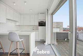 In de winkelstraat van Roeselare bevindt zich dit instapklare penthouse-appartement met twee zeer ruime terrassen. Gelegen op de zesde verdieping met panoramisch uitzicht van een verzorgd gebouw met lift, ben je op wandel- of fietsafstand van winkels, scholen en openbaar vervoer.<br /><br />Via de inkomhal betreedt u het appartement, dat leidt naar de ruime leefruimte met zit- en eethoek, die zicht en toegang biedt tot het ruime terras van 59 m² met uitzicht over de Ooststraat. Verder heeft het appartement een volledig geïnstalleerde keuken met aparte berging die naadloos overgaat tot het tweede terras van 36 m².<br />De nachthal met maatkasten geeft toegang tot twee slaapkamers, een toilet en een badkamer met dubbele wastafel en inloopdouche.<br /><br />Het appartement werd in 2015 grondig gerenoveerd, waarbij de keuken, badkamer, het parket, het raamwerk en de beglazing werden vernieuwd. Bovendien werd het volledige appartement herschilderd.<br /><br />Er kan optioneel een autostaanplaats aangekocht worden.<br /><br />Een unieke kans om te wonen in een modern, instapklaar appartement met veel licht, ruimte en zon, in het hart van Roeselare!<br /><br /><strong>Ook wild geworden van deze thuis? <br />Twijfel niet langer en leg vandaag nog uw bezoek vast! </strong>