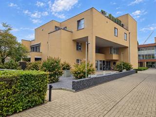 <span><strong>Ruim 2-slaapkamer appartement in residentie "De Plaetse" met zonnig terras, garagebox en private berging.<br /></strong></span><br /><span><strong>Een bezoek aanvragen kan eenvoudig via onze website: www.immodrie.be. Zoek het pand terug onder 'Te Huur' en selecteer vervolgens op de pagina de optie 'Bezoek inplannen'. Omwille van de grote reeks aanvragen, worden verzoeken via Immoscoop of andere portaalsites niet verwerkt.</strong></span><br />
<p>Bij het binnenkomen betreedt u de inkomhal, die een centrale verbinding vormt met alle vertrekken van het appartement. In de inkomhal is er bovendien ruimte voorzien voor het plaatsen van een vestiairekast, ideaal voor jassen en schoenen. Daarnaast blijft er nog voldoende open ruimte over voor een persoonlijke inrichting.</p>
<p>Vanuit de inkomhal komt u in de ruime, open leefruimte. Dankzij de aangename oppervlakte biedt deze ruimte verschillende mogelijkheden voor de inrichting van een comfortabele zithoek en een gezellige eetplaats. Vanuit de leefruimte heeft u bovendien een zicht op de halfopen hoekkeuken. Deze keuken is praktisch ingericht en voorzien van alle nodige toestellen, waaronder een vaatwasser, kookvuur en koelkast met vriesvak. Daarnaast is er voldoende opbergruimte aanwezig. Aansluitend aan de keuken bevindt zich een handige berging. Hier is de aansluiting voor de wasmachine voorzien en staat eveneens de cv-ketel.</p>
<p>Vanuit de leefruimte heeft u rechtstreeks toegang tot het zuidwestelijk georiënteerde terras. Dankzij de aanwezige zonneluifel kunt u hier op zonnige dagen heerlijk genieten, zowel overdag als tijdens de avonduren.</p>
<p>Terug in de inkomhal vinden we de toegang tot de twee slaapkamers. De eerste slaapkamer is ruim en biedt voldoende plaats voor een volwaardig bed, kasten en eventueel bijkomend meubilair. De tweede kamer is compacter en kan perfect dienstdoen als tweede slaapkamer, kinderkamer, dressing of praktische bureauruimte.</p>
<p>De badkamer is uitgerust met een ligbad met doucharmatuur en een badkamermeubel met dubbele wastafel. Daarnaast beschikt het appartement over een afzonderlijk toilet.</p>
<p>Op de kelderverdieping beschikt u over een afgesloten garagebox, voorzien van elektriciteit en verlichting. De garage is bovendien uitgerust met een elektrisch bedienbare poort. Daarnaast is er een ruime, afgesloten kelderberging aanwezig. Deze biedt mogelijkheden voor het stockeren van onder andere fietsen, vuilnisbakken, opbergrekken en allerhande huishoudelijke spullen. Ook hier zijn elektriciteit en verlichting voorzien.</p>