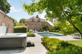Aan het einde van een doodlopende straat treffen we deze Luxueuze Manoir met oa. 4 slaapkamers, 3 badkamers, verwarmd zwembad en groot bijgebouw op een ruim perceel van ca. 2.673 m².<br /><br />Indeling gelijkvloers:<br />Via de ruime inkomhal met gastentoilet, vestiaire en statige trap komen we tot het woongedeelte. Deze bestaat uit een riante TV-kamer, een zithoek met gezellige haard en een zeer lichte eetkamer. Aansluitend bereiken we de ruime leefkeuken voorzien van een professioneel Lacanche-fornuis, vele MIELE-toestellen, eiland en plaats voor ontbijthoek. Verder geeft deze keuken ons toegang tot de een toffe en zeer lichte family-room met openhaard en mooi zicht op de aangelegde tuin en zwembad. Tevens een zeer ruime en praktische bijkeuken met plaats onder het tablet voor de wasmachine en droogkast, maatkasten en plaats voor extra wijnkoeler, diepvries en koelkast. <br /><br />Eerste verdieping:<br />Via de grote centrale overloop komen we tot de master-suite met slaapkamer 1, een grote dressing en luxueuze badkamer. Verder nog de 2e en 3e slaapkamer en de 2e luxe badkamer, voorzien van douche, bad, dubbele wastafel en toilet. <br /><br />Tweede verdieping:<br />Via de vaste trap komen we tot dit volwaardige extra verdiep. Hier treffen we een 4e slaapkamer en 3e badkamer. Verder treffen we hier ook nog een extra woonkamer welke even goed kan gebruikt worden als extra 5e slaapkamer. De mogelijkheid voor het aansluiten van een extra keuken of 4e badkamer werd voorzien. <br /><br />Kelder:<br />De trap afgewerkt met travertin brengt ons tot de volwaardige verdieping. Deze werd mooi afgewerkt en bestaat uit een wijnkelder voorzien van gemetste nissen en een aparte technische ruimte met hier de CV. ed.<br /><br />Bijgebouw:<br />Achteraan de tuin treffen we het riante bijgebouw, volledig in zelfde architectuur als de villa, momenteel gebruikt als garage, poolhouse, berging en beschikt tevens over een ruim eerste verdiep. <br /><br />BIJZONDERHEDEN<br />- Uitgebreid alarmsysteem <br />- Laadpaal<br />- Geautomatiseerde poorten met toegangscontrole en videofonie<br />- Volledige villa is voorzien airconditioning/warmtepomp<br />- Waterontharder<br />- Afgewerkt met Top-materialen!