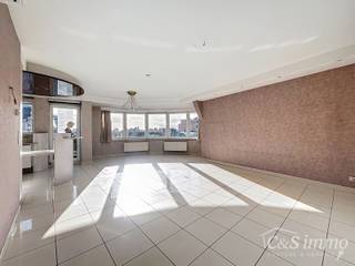 Dit unieke hoekappartement met een riant dakterras op de zesde verdieping biedt een uitzonderlijke ligging recht tegenover het oude justitiepaleis, op wandelafstand van zowel het centrum van Antwerpen als het Zuid. Dankzij de directe verbinding met de Antwerpse ring geniet de locatie bovendien van een uitstekende mobiliteitsscore.<br />Je wordt verwelkomd in een inkomhal met vestiaire en gastentoilet. De indrukwekkende, lichtrijke leefruimte (ca. 50 m²) springt meteen in het oog dankzij de iconische ronde voorgevel. Aansluitend bevindt zich de open leefkeuken (ca. 12 m²), uitgerust met afwasmachine, dampkap, kookplaat, oven, microgolfoven en een Amerikaanse koelkast met stenen werkblad. Vanuit de keuken heb je toegang tot een knus terrasje waar je ’s ochtends kan genieten van de zon en het historisch zicht op het oude justitiepaleis.<br />Via de nachthal met ingemaakte kasten bereik je een aparte berging met aansluiting voor wasmachine. De masterbedroom (21 m²) en tweede ruime slaapkamer (17 m²) liggen naast de volledig ingerichte badkamer met royaal ligbad, douche, dubbel badkamermeubel en toilet. Zowel de woonkamer als de masterbedroom geven uit op het grote terras (ca. 60 m²), perfect gericht om te genieten van de namiddag- en avondzon.<br />Het dak is conform en het appartement is energiezuinig (EPC 140 kWh/m²). Daarnaast is er een private kelderberging en is er mogelijkheid tot aankoop van een ondergrondse autostaanplaats voor €28.000.