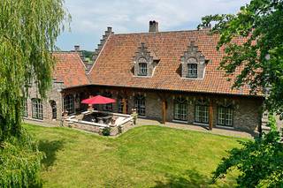 Er zijn plaatsen die veel meer zijn dan een woning. <strong>Ze vormen een bestemming op zich</strong>. Welkom op <strong>Landgoed Lindenhof</strong>, een uitzonderlijk privélandgoed waar rust, natuur en tijdloze elegantie elkaar ontmoeten.<br /><br />Verborgen achter een statige oprijlaan ontvouwt zich een prachtig aangelegd domein waar majestueuze bomen, uitgestrekte graspartijen en een indrukwekkende natuurlijke vijver samen een uitzonderlijk decor vormen. Verschillende terrassen en sfeervolle plekjes nodigen uit om op elk moment van de dag te genieten van de rust en de schoonheid van het landschap. Hier wordt het buitenleven een vanzelfsprekend onderdeel van elke dag en maakt de drukte van het dagelijkse leven plaats voor stilte, ruimte en ontspanning.<br /><br />Ook binnen ademt de villa dezelfde warme authenticiteit. De statige inkomhal met gastentoilet verwelkomt u in een interieur waar massieve eiken balken, natuurstenen vloeren, karaktervolle haarden en verfijnd maatwerk samen een tijdloze elegantie creëren. De royale leefruimtes bieden een prachtig uitzicht op het omliggende groen, terwijl de landelijke leefkeuken uitnodigt tot lange avonden met familie en vrienden.<br /><br />De hoofdwoning beschikt over <strong>vijf volwaardige slaapkamers</strong>, waarvan één slaapkamer op het gelijkvloers, ideaal als bureau of gastenkamer. Op de eerste verdieping bevinden zich nog <strong>vier ruime slaapkamers</strong> en twee stijlvolle badkamers, waardoor de villa perfect aansluit bij grotere gezinnen of wie graag gasten ontvangt.<br /><br />Een absolute troef van <strong>Landgoed Lindenhof</strong> is het afzonderlijke gastenverblijf met een gezellige leefruimte en bar op het gelijkvloers en een slaapkamer op de verdieping. Deze veelzijdige ruimte biedt tal van mogelijkheden als gastenverblijf, ontspanningsruimte, praktijk aan huis of verblijf voor inwonende familie. Daarnaast beschikt het domein over een ruime werkplaats met garage, ideaal voor zelfstandigen, hobbyisten of het veilig stallen van voertuigen en materiaal.<br /><strong>Landgoed Lindenhof is meer dan een exclusieve villa</strong>. Het is een plek waar natuur, architectuur en levenskwaliteit elkaar ontmoeten. Een eigendom die uitnodigt om te onthaasten, te genieten en elke dag opnieuw de rust van een uitzonderlijk privélandgoed te ervaren.<br /><br /><strong>Ontdek Landgoed Lindenhof</strong><br />De ware schoonheid van Landgoed Lindenhof openbaart zich pas wanneer u het domein zelf ervaart. Contacteer ons voor een exclusieve rondleiding en ontdek de unieke harmonie tussen architectuur, natuur en levenskwaliteit die Landgoed Lindenhof zo bijzonder maakt.<br />