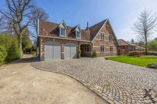 In de residentiële wijk ‘Den Drijhoek’ te Schilde, een buurt die bekendstaat om haar rustige en groene karakter bevindt zich deze indrukwekkende villa op een royaal perceel. Bij het betreden van de woning via de elegante inkomhal met gastentoilet, wordt u direct omarmd door een sfeer van tijdloze klasse. De royale L-vormige leefruimte ademt karakter dankzij de massieve parketvloer, authentieke balkenpartijen en sfeervolle haarden.
Aansluitend vindt u de droom van elke culinaire liefhebber: een hyper-uitgeruste keuken waar enkel genoegen is genomen met het beste. Terwijl de knalrode elektrische AGA de show steelt, zorgen de Sub-Zero koel-vriescombinatie en het keukeneiland met wijnkoeler en professionele wokplaat voor een gastronomische ervaring op topniveau.
Het doordachte ontwerp biedt u het comfort van een grote slaapkamer op het gelijkvloers met aparte toegang van buiten. Vanuit deze slaapkamer ontwaakt u met een rustgevend uitzicht op de tuin en het zwembad, terwijl de dressing met maatwerk en de en-suite badkamer met inloopdouche een gevoel van hotelsuite-luxe geven.
Op de verdieping leidt een riante overloop naar een master suite met en-suite badkamer en nog 3 royale slaapkamers. Een derde badkamer en een separate wasplaats vervolledigen dit niveau.
Buiten transformeert het perceel in een private oase. Het verwarmde zwembad wordt omringd door zonneterrassen, overdekte terrassen en een sfeervolle patio met buitenhaard, de ideale plek voor lange zomeravonden. Deze villa is technisch klaar voor de toekomst met zonnepanelen, airco, camerabewaking, een oplaadpunt voor elektrische wagens en tuinberegening. Een dubbele garage en een koele wijnkelder maken dit unieke plaatje compleet. Een residentie waar luxe, veiligheid en leefplezier elkaar ontmoeten. Plan vandaag nog uw bezoek in en laat u betoveren door deze prachtige woning.