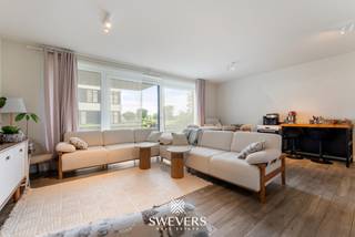 Voor meer info en foto’s, surf naar www.swevers.be – Dit instapklare gelijkvloerse appartement ligt aan de achterzijde van residentie Zuidzicht op Scheepvaartlaan 48/0.05 in Hasselt. Dankzij deze rustige ligging geniet u van zicht op de binnentuin en een glimp van het Albertkanaal. Het appartement werd gebouwd in 2016, is bereikbaar met de lift en biedt een bewoonbare oppervlakte van 74,38 m². De indeling bestaat uit een inkomhal, twee slaapkamers, een badkamer en een ruime leefruimte met open keuken. De woonkamer en keuken vormen samen een aangename leefzone met veel licht en directe toegang tot het overdekte terras van maar liefst 30 m². Dit terras is een grote troef en voelt aan als een verlengstuk van de leefruimte. De hoofdslaapkamer is volwaardig ingericht, terwijl de tweede kamer perfect dienst kan doen als bureau, kinderkamer, logeerkamer of dressing. De badkamer beschikt over een ligbad met douchescherm en een ruime wastafel. Met EPC-score B is het appartement bovendien energiezuinig. Het pand is momenteel verhuurd aan 890 euro per maand, plus 125 euro gemeenschappelijke kosten, wat het ook interessant maakt als investering. Een ondergrondse autostaanplaats kan optioneel aangekocht worden voor 32.500 euro. Dankzij de ligging nabij het centrum van Hasselt bevinden winkels, horeca, ontspanning, scholen, openbaar vervoer en de autosnelweg zich allemaal vlot bereikbaar. Voor meer informatie, bel 011 255 155. Bron bewoonbare oppervlakte: EPC – verslag.