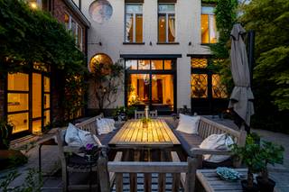 <p><strong><span>Groot Breda – Uitzonderlijk wonen in het hart van Turnhout<br /><br /></span></strong><span>In het centrum van Turnhout, op wandelafstand van winkels, horeca, scholen en alle dagelijkse voorzieningen, bevindt zich ‘Groot Breda’: een bijzonder ruime stadswoning waar karakter, privacy en wooncomfort op een unieke manier samenkomen.<br /><br /></span><span>Achter de statige gevel schuilt een verrassend royale woning met hoge plafonds, grote leefruimtes en authentieke elementen zoals parketvloeren, moulures, loodglas en een karaktervolle schouw. De verschillende vertrekken sluiten mooi op elkaar aan en bieden dankzij hun afmetingen bijzonder veel woonmogelijkheden.<br /><br /></span><span>De leefruimtes genieten van veel licht en kijken achteraan uit op het groen. De eetkamer vormt een aangename verbinding met de tuin, terwijl de volledig uitgeruste keuken beschikt over onder meer twee Smeg-ovens, een Miele-vaatwasser, inductiekookplaat en een natuurstenen werkblad.<br /><br /></span><span>Op de eerste verdieping bevinden zich meerdere ruime slaapkamers, een kantoor met zicht op het groen en een master suite met ingemaakte kasten, dressing, ensuite badkamer en apart toilet. De tweede verdieping biedt bijkomende slaapkamers, een extra badkamer en multifunctionele ruimtes die perfect kunnen dienen als bureau, hobbykamer, dressing of logeerkamer.<br /><br /></span><span>Dankzij de stevige structuur van de woning, de hoge ruimtes en de volwassen bomen rondom blijft het binnenklimaat ook tijdens warme zomerdagen opvallend aangenaam en koel.<br /><br /></span><strong><span>De absolute troef bevindt zich achteraan.</span></strong><span> Hier ontvouwt zich een uitzonderlijk diepe, groene en private tuin die een gevoel van rust creëert dat zelden te vinden is in het stadscentrum. Volwassen bomen zorgen voor beschutting en verkoeling, terwijl de lange zichtlijnen de tuin een bijzonder ruim karakter geven.<br /><br /></span><span>Centraal in deze groene omgeving ligt het verwarmde zwembad van 6 x 10 meter. Het ruime terras sluit rechtstreeks aan bij de woning en vormt een natuurlijke overgang tussen binnen en buiten. Vanuit de tuin geniet u bovendien van een prachtig zicht op de Sint-Pieterskerk.<br /><br /></span><span>Het achterliggende binnengebied zal in de toekomst verder vergroenen, wat het open en groene karakter van deze uitzonderlijke ligging nog versterkt.<br /><br /></span><span>Ook praktisch biedt Groot Breda heel wat comfort. Aan de woning zelf is er mogelijkheid tot twee staanplaatsen via de inpandige garage. Daarnaast zijn er op slechts 1-2 minuten wandelen bijkomende parkeermogelijkheden.<br /><br />Bijzonderheden: <br />- Uitzonderlijk ruime stadwoning <br />- Grote, private en groene tuin met verwarmd zwembad <br />- Aangenaam koel binnenklimaat <br />- Inpandige parkeermogelijkheid voor twee wagens <br />- Bijkomende parkeermogelijkheden op ca. 1-2 minuten wandelen <br />- Gewelfde wijnkelder <br />- Twee afzonderlijke verwarmingscircuits <br />- Alarmsysteem <br />- Beschermd monument <br />- Centrale ligging nabij alle voorzieningen <br /><br /><strong>‘Groot Breda’ combineert uitzonderlijk veel ruimte, volledige privacy, een prachtige groene tuin en alle voorzieningen binnen handbereik. Een woning die achter haar gevel een onverwachte wereld van rust, ruimte en groen verbergt.</strong><br /></span></p>