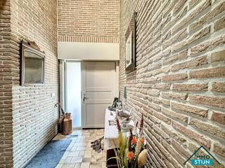 Deze ruime woning ligt in een rustige, doodlopende straat op een steenworp van diverse winkels, het openbaar vervoer en met een vlotte verbinding naar de E403. Ideaal voor wie graag rustig woont zonder in te boeten aan bereikbaarheid! Je komt de woning binnen via de inkomhal die overloopt in de nachthal. Vanuit de inkom bereik je zowel de gezellige woonkamer als de praktische dubbele garage. De lichtrijke woonkamer biedt alle ruimte voor een zit- en eetgedeelte en sluit mooi aan op de hyper-geïnstalleerde keuken. Aansluitend vind je een sfeervolle leefveranda die baadt in het licht en een prachtig zicht biedt op de fraai aangelegde tuin. Naast de keuken is er een handige wasplaats en via de nachthal bereik je de eerste slaapkamer, een gastentoilet, een bergruimte en de eerste badkamer. Deze badkamer werd in 2005 vernieuwd en beschikt over een ligbad, douche en dubbel lavabomeubel.<br />Op de eerste verdieping vind je de nachthal, vier ruime slaapkamers en een tweede badkamer met lavabo, toilet en douche. De woning is voorzien van alle extra’s die bijdragen aan comfort en duurzaamheid: een regenwaterput, een boorput, 16 zonnepanelen en airco in de veranda. De centrale verwarming op mazout houdt de woning het hele jaar door aangenaam warm.<br />Buiten geniet je van een prachtig aangelegde voortuin die doorloopt naar de achtertuin met gezellige terrasjes, wandelpaden en tuinhuizen. De lange oprit leidt je langs de woning heen tot achteraan, ideaal voor meerdere wagens. (sted. inl.: in aanvraag)