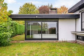 Ruimte, karakter en tal van mogelijkheden! Deze alleenstaande architectenvilla combineert royale leefruimtes met een praktische indeling en een aparte praktijkruimte. Ideaal voor wie comfortabel wil wonen en werken op één locatie.Via de ruime inkomhal betreed je de lichtrijke leefruimte, die bestaat uit een gezellige zithoek met open haard, een ruime eetplaats en praktische ingemaakte kasten. Aansluitend bevindt zich de volledig uitgeruste keuken. De veranda vormt een aangename extra leefruimte met zicht op de tuin.Op de verdieping bevinden zich drie slaapkamers, waarvan twee uitgerust zijn met ingemaakte kasten. De vernieuwde badkamer biedt alle comfort, met een inloopdouche, ligbad en dubbel lavabomeubel.Een absolute meerwaarde is de aparte praktijkruimte van bijna 50 m². Dankzij de eigen ingang, vier afzonderlijke ruimtes en een eigen toilet is deze perfect geschikt voor een kantoor, praktijk, vrij beroep of hobbyruimte.Ook op praktisch vlak heeft deze woning heel wat te bieden: een dubbele garage met wasplaats en bergruimte, aangevuld met vier parkeerplaatsen op het eigen terrein.De ligging langs de Moeskroensesteenweg garandeert een vlotte verbinding naar Aalbeke, Kortrijk en Moeskroen.Wenst u graag een bezoek of meer informatie, neem dan contact op via flore@immobeguin.be