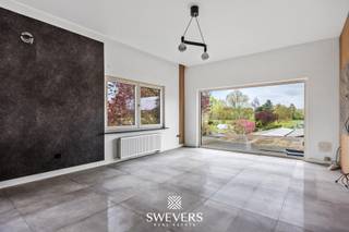 Voor meer info en foto’s, surf naar www.swevers.be – Dit ruime en instapklare appartement op de eerste verdieping in de Larenstraat 67 in Lummen werd oorspronkelijk gebouwd in 1976 en kreeg in 2022 een grondige renovatie. Met een bewoonbare oppervlakte van 123 m² en gelegen op een perceel van 14a 25ca geniet u hier van een hedendaagse afwerking, veel lichtinval en een praktische indeling. De centrale inkomhal leidt naar de lichtrijke leefruimte van 33,6 m², waar u vlot een gezellige zithoek en eethoek kan inrichten. Aansluitend bevindt zich de functionele keuken van 10 m², die mooi aansluit op het leefgedeelte. Het appartement beschikt over maar liefst 4 volwaardige slaapkamers van 11,5 m², 11 m², 11 m² en 23 m². De grootste kamer biedt extra mogelijkheden als master bedroom met dressing of bureau. In alle slaapkamers ligt parket, wat zorgt voor een warme uitstraling. De badkamer is uitgerust met een douche en er is een apart toilet aanwezig. Extra troeven zijn de privatieve garage van 20 m², de ruime gemeenschappelijke tuin van 876 m² met noordelijke oriëntatie en de aanwezigheid van 24 zonnepanelen. Ook de ligging is bijzonder praktisch, met scholen en ontspanning op 500 meter, een bushalte op 190 meter, winkels en restaurants binnen 2 km en de snelweg op slechts 2,5 km. Een ruim en verzorgd appartement met hedendaags comfort, veel mogelijkheden en een vlotte bereikbaarheid. Voor meer informatie, bel 012 699 900. Bron bewoonbare oppervlakte: EPC – verslag.
