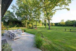 Verscholen in een oase van rust en groen, bereikbaar via een private oprijlaan, bevindt zich deze architectenvilla van de hand van architect J.C. Bols op 13.815 m² grond. Een eigendom waar discretie en hedendaags wooncomfort harmonieus samenkomen, op een toplocatie op slechts enkele minuten van het centrum van Turnhout. Deze imposante villa werd in 2020 quasi volledig gerenoveerd met respect voor haar karaktervolle architectuur, en afgewerkt met hoogwaardige materialen doorheen de volledige woning. Het resultaat is een instapklare villa met een tijdloze uitstraling, ontworpen voor wie comfortabel wil wonen in volledige privacy.<br /><br />Bij het betreden van de woning verwelkomt een stijlvolle inkomhal u in een wereld van elegantie en ruimte. Er is een praktische bureauruimte aanwezig, te bereiken vanuit deze inkomhal. De royale leefvertrekken baden in natuurlijk licht en genieten van een prachtig zicht op het omliggende groen. De sfeervolle zithoek met geïntegreerd maatwerk en uitnodigende eetkamer creëren een warm en verfijnd geheel. De volledig vernieuwde leefkeuken vormt het hart van de woning en is uitgerust met alle hedendaagse comfort voorzien van alle moderne apparatuur. De aanpalende ontbijtruimte geeft rechtstreeks toegang tot het terras.<br /><br />De villa beschikt over vijf volwaardige slaapkamers en twee badkamers. De mastersuite omvat een recent vernieuwde badkamer en dubbele dressing. Een aparte vleugel met eigen toegang en trap biedt bijkomende mogelijkheden als gastenverblijf of kantoor.<br /><br />De zolderverdieping strekt zich uit over de volledige woning en biedt veel potentieel voor extra slaapkamers of hobbyruimte.<br /><br />Ook op praktisch vlak voldoet deze eigendom aan de hoogste verwachtingen, met onder meer een dubbele inpandige garage, ruime kelderverdieping inclusief wijnkelder, alarm, airconditioning en een duurzame energievoorziening dankzij zonnepanelen met batterijopslag.<br /><br />Het volledig omheinde domein omvat een prachtig aangelegde tuin met meerdere natuurstenen terrassen, een sfeervol paviljoen met open haard, ruime parkeergelegenheid en een weiland met dierenstal. Een zeldzame plek waar rust, natuur en absolute privacy centraal staan.<br /><br />Bijzonderheden: <br />- zeer mooi gelegen, in het groen, aan de rand van Turnhout. <br />- de villa werd gerenoveerd in 2020 en werd hedendaags afgewerkt<br />- groot woonvolume van 557 m²<br />- verwarming dmv van propaangas (deels vloerverwarming en deels radiatoren)<br />- 24 zonnepanelen en batterij aanwezig