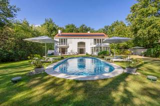 <p>Zoekt u het ultieme vakantiegevoel zonder uw huis te verlaten? Dan is deze villa de perfecte woning voor u. Deze luxe, moderne en zeer lichte villa bevindt zich in de groene, residentiële Bellemond wijk op een toplocatie te ’s Gravenwezel. Hier geniet u van volledige privacy in een prachtige zuidwest-georiënteerde tuin met een verwarmd zwembad. De villa is ideaal gelegen nabij scholen, openbaar vervoer en winkels, en ligt in een van de meest prestigieuze wijken van ’s Gravenwezel.</p>
<p>Deze architectenwoning, ontworpen door de gerenommeerde architect John Bontinck, is gebouwd met hoogwaardige materialen. De visie van de architect om de tuin sterk bij de woning te betrekken, is werkelijk verbluffend geslaagd. Bij binnenkomst wordt u meteen gecharmeerd door het vakantiegevoel dat de villa uitstraalt. Een prachtige doorkijk naar de tuin en het zwembad verwelkomt u direct.<br /><br />INDELING<br /><br /><strong>Gelijkvloers:<br /></strong>Bij binnenkomst wordt u meteen gecharmeerd door het vakantiegevoel dat de villa uitstraalt. Een prachtige doorkijk naar de tuin en het zwembad verwelkomt u direct. <br />U treedt de villa binnen via een inkomhal met een apart gastentoilet en een ruime vestiaire. Een dubbele glazen deur biedt toegang tot de riante en lichte woonkamer met een doorlopend raam tot de verdieping. De leefruimte, verdeeld in zithoek, salon en eetkamer, is voorzien van een eiken parketvloer en een prachtig open haard. De ruimtes vloeien mooi in elkaar over en zijn in direct contact via grote deurramen met het zuidwest-georiënteerde terras, de tuin en het zwembad.<br /><br />Aansluitend aan de leefruimte vindt u de volledig geïnstalleerde keuken met een kookeiland, ontbijthoek, tal van opbergkasten en moderne toestellen, waaronder een Amerikaanse koelkast. Door kamerhoge raampartijen rondom de keuken wordt deze ruimte overspoeld met natuurlijk licht en biedt het een prachtig uitzicht op de tuin en het zwembad.<br /><br />Een praktische douchekamer met toegang naar buiten is ideaal na een zwembeurt in het zwembad.<br /><br />Een mooie houten trap leidt naar de eerste verdieping, waar een impressionante vide extra licht en uitzicht biedt vanuit de verdieping op de prachtige tuin.<br /><br /><strong>1e Verdieping:<br /></strong>Op de 1e verdieping vindt u de mastersuite met dressing en badkamer – met ligbad, dubbele lavabo en toilet. De 2e slaapkamer (ca. 31m²) op parket met ingemaakte kasten geeft uit op een prachtig terras. De 2e (ca. 20m²) en 4e slaapkamers (ca. 18m²) delen de 2e badkamer met ligbad, lavabo en toilet. Verder is er nog een handige berging, ideaal voor een linnenkast of een extra douchekamer.<br /><br /><strong>Tuin en Zwembad<br /></strong>Geniet volop van de zonnige tuin in volledige privacy zonder enige inkijk. De tuin is aangelegd met verschillende terrassen, een verwarmd zwembad en een tuinhuis. Deze buitenruimte biedt de perfecte setting voor ontspanning, zomerse barbecues en gezellige avonden.<br /><br />Een inpandige garage biedt ruimte voor 2 wagens en heeft een automatische toegangspoort. Daarnaast is er een ruime oprit met plaats voor meerdere wagens, wat extra gemak en parkeerruimte biedt voor u en uw gasten.<br /><br />Kortom, deze villa is een waar paradijs voor wie houdt van een luxe levensstijl met een vleugje vakantie. De ruime indeling en grote ramen zorgen voor een lichte en luchtige sfeer. Mis deze unieke kans niet om in een van de meest gewilde wijken van ’s Gravenwezel te wonen.</p>
<p></p>
<p>BIJZONDERHEDEN:<br />+ Architect John Bontinck<br />+ Nieuw gietvloeren op verschillende ruimtes<br />+ Vloerverwarming <br />+ 15 zonnepanelen (2024)<br />+ Gunstig EPC: 164kWh/m²<br />+ Vloerverwarming op GLV<br />+ Asbestvrij.<br />+ Bose audio-installatie in alle ruimtes, voor optimale geluidservaring.<br /><br />Voor meer informatie of een bezoek aan deze gezellige woning, neem gerust contact op met Sigalit via Sigalit@reds.be of op 0475668474</p>