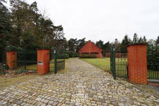 Deze gelijkvloerse charmante woning biedt zeer veel mogelijkheden voor wie op zoek is naar een woning met eventueel praktijk aan huis. Ook als ruim gezinspand met dubbele inpandige garage, grote kelder en zeer veel privacy is dit ideaal! <br />Dit praktisch ingedeeld huis geniet een mooie uitstraling en heeft ruime kamers met nog veel extra uitbreidingsmogelijkheden op de verdieping. <br />Dit karaktervolle pand ligt op een groot perceel te bereiken via een mooie oprijlaan. De gunstige en vlot bereikbare locatie tegen groen maar ook vlakbij autostrade, ZOL en centrum Genk zijn ideaal voor wie gemak wil combineren met luxueus en vrij wonen. <br />Kortom, een eigendom met karakter en potentieel, klaar om verder naar jouw wensen ingevuld te worden!!<br /><br />=> Gelijkvloers<br />- Royale inkomhal met toegang naar leefruimte en keuken<br />- Eveneens toegang tot de nachtgang vanuit de centrale inkomhal<br />- Ruime woonkamer met inbouwhaard in sierschouw<br />- Rechtstreeks toegang tot het terras aan de achterzijde<br />- Aparte keuken voorzien van alle comfort<br />- Vaste eettafel in de keuken<br />- Rechtstreekse deur naar tuin vanuit de keuken<br />- Gang met gastentoilet met fonteintje en vaste trap naar de verdieping<br />- Twee ruime slaapkamers<br />- Twee kleinere slaapkamers<br />- Bureelruimte, direct naast de inkomhal<br />- Volledig betegelde badkamer met ligbad, douche en wastafel<br /><br />=> Kelder en zolder<br />- De woning is volledig onderkelderd en te bereiken enerzijds via de keuken en anderzijds via de grote inpandige garage<br />- De verdieping van de woning is via een vaste trap te bereiken en biedt nog veel uitbreidingsmogelijkheden<br />- Volwaardig te benutten etage met grote ruimtes<br /><br />=>Tuin<br />- Zeer royaal perceel van ca. 1ha ideaal voor het houden van paarden of diertjes<br />- Woning te bereiken via eigen oprijlaan<br />- Mooi terras aan de achterzijde met maximale privacy in natuurlijke omgeving om in alle rust te genieten<br />- De tuin rondom de woning kan nog aangelegd worden naar eigen wens en loopt naadloos over in nog meer groen en bos<br /><br />=> Indeling<br />- Gelijkvloers: inkomhal, gastentoilet, woonkamer, keuken, bureel, twee grote slaapkamers, twee kleinere slaapkamers, badkamer, dubbele inpandige garage<br />- Verdieping/zolder: te bereiken via een vaste trap en in te richten tot extra kamers<br />- Kelder - volledig onderkelderd: CV- ruimte, voorraadkelder, diverse opbergruimtes