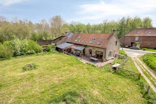 This unique long-facade farmhouse enjoys a quiet location next to a forest, just 15 minutes from Brussels. Nature lovers will be thrilled by the immediate proximity of the Zuun valley. This property offers the perfect balance between rural tranquility and excellent accessibility.The farmhouse has a living area of 320 m² on a generous 21.25-are plot. You have the option to purchase the adjacent, bio-certified land featuring around twenty fruit trees (91.60 ares). This brings the total area to 1.12 hectares. Additional assets include a groundwater well and a beautiful cobblestone driveway with space for four cars.On the ground floor, you will find a spacious entrance hall with a guest toilet and a room currently used as an office, which could easily serve as a bedroom. The bright kitchen features a large 110 cm gas stove, a scullery, and a storage room. The living room, with a beautiful fireplace and sliding doors to the large terrace, forms the heart of the home. The terrace provides access to a spacious studio. Furthermore, there is an indoor garage for one car.The first floor offers two very spacious bedrooms, each with an en-suite bathroom. A long hallway leads to two extra bedrooms, a third bathroom/laundry room, and a toilet. 9 Velux skylights bathe the entire floor in natural light, offering stunning views of the garden, woods, and fields. Seize this unique opportunity to own this beautiful domain.Register of measures: no
