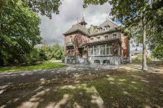 Bent u op zoek naar een historisch pareltje met een unieke uitstraling? Deze statige villa in Anzegem, gebouwd rond 1900 in opdracht van dokter Vancauwenberghe, combineert authentieke charme met opvallende architectuur. <br /><br />De woning ligt wat dieper op het perceel, wat zorgt voor een aangename privacy, en is aan de straatzijde stijlvol afgesloten met een bakstenen muurtje en een sierlijk ijzeren hekwerk.<br /><br />De beeldbepalende woning betreft een eclectisch dubbelhuis met duidelijke invloeden uit de neo-Vlaams-renaissance. Dat uit zich onder meer in de karakteristieke puntgevel, het sierlijke torentje aan de westzijde en het verfijnde gebruik van hoogwaardige bouwmaterialen. De gevel van rode baksteen is verfraaid met siermetselwerk van geglazuurde accenten en zwarte bakstenen ruitmotieven. Daarnaast is er rijkelijk gebruikgemaakt van blauwe hardsteen (arduin) voor het bordes, de hoekblokken, tussenstijlen, aanzet- en dekstenen. Het leien dak is voorzien van twee dakkapellen en wordt bekroond door sierlijke bliksemafleiders.<br /><br />Ook de gevelindeling en het gedetailleerde houtwerk springen meteen in het oog. De vooruitspringende deurtravee en de brede venstertravee worden geaccentueerd door een klassiek bow window op het gelijkvloers en een driedelige houten erker op de eerste verdieping. Alle getoogde raam- en deuropeningen beschikken bovendien over bewaard gebleven authentiek schrijnwerk. Naast de villa bevindt zich een ruime garage die volledig in dezelfde architecturale stijl werd opgetrokken. Deze beschikt over twee poorten — waarvan één vernieuwd — onder robuuste ijzeren I-balken, wat het geheel op esthetisch vlak prachtig compleet maakt.<br /><br />INDELING<br />- Inkomhal, riante leefruimtes, ruime keuken, bureau, praktijkruimte <br />- 9 slaapkamers<br />- Volledig onderkelderd<br />- Terras - ruime tuin - koetshuis - garage<br /><br />Deze eigendom wordt aangeboden via het power-sale concept die loopt tot en met 23 oktober.<br /><br />Wenst u dit uitzonderlijke vastgoed in Anzegem te ontdekken? Neem dan contact op met Matisse Vandererven (0472/186420) of Carl Boedts (0473/951821) voor meer informatie of een bezoek.<br /><br /><br /><br />Bestuursmaatregelen in het maatregelenregister: nee