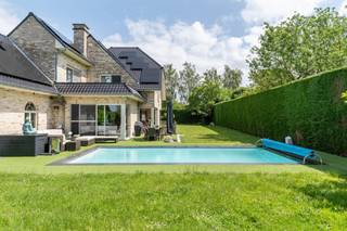 Deze exclusieve, vrijstaande villa in landelijke stijl in Wemmel straalt pure klasse uit. Met een royale bewoonbare oppervlakte van 526 m² en een superieure afwerkingsgraad geniet u hier van uitzonderlijk wooncomfort. De zandkleurige gevel combineert harmonieus met charmante dakkapellen en een monumentale glaspartij bij de inkom. De woning is energie-efficiënt uitgerust met zonnepanelen en een hoogwaardig alarmsysteem.<br /><br />De villa ligt op een discreet perceel, volledig aan het oog onttrokken via een lange privé-inrit. Dit garandeert honderd procent privacy en sereniteit, terwijl scholen, openbaar vervoer en de Brusselse Ring (R0) vlakbij zijn.<br /><br />Binnen opent de inkomhal in een spectaculaire vide met een marmeren trappartij. De centrale leefruimte ademt licht dankzij kamerhoge schuiframen naar de tuin. De living beschikt over een formele eethoek, een zithoek met maatwerkkasten en een sfeervol tweede salon met gashaard. Daarnaast is er een onafhankelijke praktijk- of kantoorruimte op het gelijkvloers.<br /><br />De high-end leefkeuken met werkeiland en premium Miele-apparatuur sluit naadloos aan op het terras. Op de verdieping biedt de mezzanine toegang tot vier grote slaapkamers met ingebouwde kasten en drie stijlvolle, moderne badkamers. De master suite beschikt over een eigen dakterras.<br /><br />De prachtig aangelegde tuin is omzoomd door hoge hagen en beschikt over een strak buitenzwembad met hardhouten zonneterrassen. Aan de voorzijde biedt de oprit plaats voor een tal van wagens.<br /><br />Bestuursmaatregelen in het maatregelenregister: nee