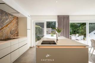Wonen in een strakke, hedendaagse BEN-woning in een kindvriendelijke en uiterst praktische omgeving in Wondelgem? Deze halfopen bebouwing, gebouwd in 2020, combineert hedendaagse architectuur met hoogwaardige materialen, doordacht maatwerk en een bijzonder aangenaam wooncomfort.<br /><br />Achter de strakke witte gevel, gecombineerd met warme houten accenten aan de gevel en garagepoort, schuilt een instapklare gezinswoning waar functionaliteit en esthetiek mooi in balans zijn.<br /><br />Karaktervolle leefkeuken<br />De open leefkeuken vormt het hart van de woning en is afgewerkt met hoogwaardige materialen. De indrukwekkende marmeren achterwand, een eiland met dubbele spoelbak en de discreet geïntegreerde designverlichting zorgen voor een eigentijdse en sfeervolle uitstraling. Een ideale ruimte om dagelijks te genieten, maar ook om familie en vrienden te ontvangen.<br /><br />Doordachte indeling en hoogwaardig maatwerk<br />Met een bewoonbare oppervlakte van 158 m² biedt de woning een bijzonder comfortabele en praktische indeling.<br />Op de verdieping bevinden zich drie slaapkamers. Eén van de kamers is momenteel ingericht als multifunctionele ruimte, met ingemaakte kasten, een bureau en een geïntegreerd 'verborgen' bed. Dankzij de slimme indeling en hoogwaardige afwerking kan deze ruimte zowel als volwaardige bureauruimte als slaapkamer of logeerkamer worden gebruikt. De aangename natuurlijke lichtinval maakt de kamer bovendien bijzonder geschikt als werk- of slaapruimte.<br /><br />De badkamer is afgewerkt met een eigentijdse inrichting en beschikt over een strakke inloopdouche en een elegant dubbel wastafelmeubel. De leidingen voor de plaatsing van een bad zijn reeds voorzien. Zowel op het gelijkvloers als op de verdieping is er een afzonderlijk gastentoilet.<br /><br />Doorheen de woning werd gekozen voor onderhoudsvriendelijke keramische vloeren in combinatie met vloerverwarming. Marmer- en eikaccenten, aangevuld met talrijke kamerhoge maatkasten, zorgen voor een rustige en kwalitatieve afwerking met een optimale benutting van de beschikbare ruimte.<br /><br />Exclusieve troeven op een rij<br />-Instapklaar<br />-Ingebouwde koffiecorner<br />-Verfijnd maatwerk en hoogwaardige materialen<br />-Vloerverwarming doorheen de woning<br />-Energiezuinige BEN-woning met zonnepanelen (thuisbatterij niet inbegrepen) en laadpaal<br />-Geïntegreerd alarmsysteem <br /><br />Achteraan geniet de woning van een aangenaam aangelegd terras en een onderhoudsvriendelijke tuin, omringd door groen. Het praktische tuinhuis biedt bijkomende bergruimte. De inpandige garage biedt plaats aan een wagen en fietsen en zorgt bovendien voor een rechtstreekse verbinding met de woning.<br /><br />Praktisch en rustig wonen in Wondelgem<br />De woning bevindt zich in Wondelgem, ten noordwesten van Gent, en geniet van een bijzonder praktische ligging. Een rustige, kindvriendelijke woonomgeving wordt hier gecombineerd met een vlotte bereikbaarheid van de belangrijkste invalswegen en het openbaar vervoer.<br /><br />Ook voor gezinnen is de ligging bijzonder interessant. Scholen zoals de Daltonschool (ca. 653 m) en basisschool Klimrek Van Belle (ca. 794 m) bevinden zich op korte wandel- of fietsafstand.<br /><br />Voor de dagelijkse voorzieningen hoeft u bovendien niet ver te gaan: een apotheek, huisarts, park, speeltuin en supermarkten zoals Colruyt en Carrefour Express bevinden zich allemaal binnen een straal van ongeveer 1 kilometer. Een uitzonderlijke, energiezuinige gezinswoning met hoogwaardige afwerking, veel maatwerk en een bijzonder praktische ligging in Wondelgem.