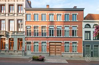 In het centrum van Ronse bevindt zich deze uitzonderlijke eigendom, bestaande uit twee afzonderlijke wooneenheden. De statige voormalige directeurswoning combineert authentieke architectuur en karaktervolle elementen met royale volumes, hedendaags wooncomfort en tal van mogelijkheden.Wijnstraat 44 – karakter, ruimte en grandeur:Via de ruime, overdekte galerij met plaats voor twee wagens bereikt u de imposante herenwoning. Hoge plafonds, sierlijsten, authentieke vloeren en karaktervolle schouwen springen meteen in het oog.Op het gelijkvloers bevinden zich verschillende ruime leef- en ontvangstruimtes. Dankzij hun indeling lenen deze zich uitstekend voor wie wonen en werken wil combineren, bijvoorbeeld als kantoor, praktijkruimte of voor de uitoefening van een vrij beroep.Achteraan bevindt zich een afzonderlijke leef- en zitruimte met zicht op de groene stadstuin, met aansluitend de ingerichte keuken. Zo kunnen professionele en private ruimtes mooi van elkaar gescheiden worden.De eerste en tweede verdieping omvatten samen vijf slaapkamers en twee badkamers. Daarnaast is er op de eerste verdieping, bereikbaar via een aparte trap, een grote polyvalente ruimte, ideaal als atelier, hobbyruimte, praktijk, kantoor of extra leefruimte. Ook een praktische (wijn)kelder is aanwezig.De prachtige stadstuin vormt een oase van rust en privacy. Het ruime terras en de jacuzzi maken het geheel compleet.Technisch:- Conforme elektrische installatie- EPC-label D- 36 zonnepanelen, geplaatst na opmaak van het EPC-attest en dus nog niet meegerekend- Regenwaterput- Laadpaal- Centrale verwarming op stookolie (conformiteitskeuring aanwezig)- Airconditioning in bepaalde slaapkamers- WaterverzachterWijnstraat 42 – investeringseigendom:Het tweede gedeelte is een afzonderlijke, recent gerenoveerde woning met eigen toegang. Op het gelijkvloers bevinden zich een woon- en leefruimte, keuken, bureau/slaapkamer en koertje. De eerste verdieping telt twee slaapkamers.De woning is momenteel verhuurd voor € 775/maand op basis van een jaarcontract en biedt zo een onmiddellijke huuropbrengst.Een zeldzame eigendom, ideaal voor een groot gezin, vrij beroep, wonen en werken, kangoeroewonen of de combinatie van eigen bewoning en verhuur.Een unieke combinatie van grandeur, wooncomfort en opbrengstpotentieel in hartje Ronse.Graag meer info en een bezoek? Caroline@immobeguin.be