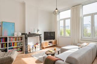 <p><strong>Berchem is zo’n plek die voorziet van al het nodige. Je zit hier tussen stad en rust, met winkels, scholen en verbindingen letterlijk om de hoek. Geen gedoe, geen omwegen - gewoon een buurt die leeft. En in de Uitbreidingstraat, in een kleinschalig gebouw, stellen we je vandaag voor aan een appartement dat dat gevoel helemaal doortrekt. Geen klassiek appartement, maar een triplex. Drie verdiepingen, elk met hun eigen ritme, hun eigen sfeer. En overal datzelfde warme fundament: parket onder je voeten, licht dat binnenvalt langs beide kanten en authentieke elementen waar je ook kijkt. Benieuwd? Kom binnen… </strong><br /></p><p><strong>Binnenkomen en meteen karakter</strong></p><p>Je komt binnen in het appartement en staat meteen in de praktisch ingerichte keuken. Geen lange gangen of verloren ruimte, maar een directe binnenkomer. Aansluitend vind je de badkamer, bereikbaar via de keuken. Die is voorzien van een bad, een enkel lavabomeubel en een toilet. Ook de aansluiting voor wasmachine en droogkast zit hier netjes verwerkt. Alles wat je nodig hebt - compact en logisch samengebracht.<br /></p><p><strong>Leven op hoogte</strong></p><p>Een trap hoger kom je in de leefruimte. De eetruimte en living vloeien hier in elkaar over, met langs beide kanten ramen die het licht binnenlaten. Ochtendzon langs de ene kant, avondzon langs de andere - de dag speelt zich hier gewoon vanzelf af. De recent opgeschuurde en verniste parketvloeren geven de ruimte warmte en karakter, terwijl de authentieke elementen - moluren, rosetten, haarden - zachtjes herinneren aan het verleden van het gebouw. Geen overdaad, wel charme die blijft hangen.<br /></p><p><strong>Slapen onder het dak</strong></p><p>Nog een trapje hoger kom je op de bovenste verdieping, waar de rust je elke dag opwacht. De master bedroom voelt ruim en rustig aan - en aansluitend ligt de dressing, opgevat als doorloopruimte, die zorgt voor extra comfort en opbergruimte. Daarnaast is er nog een tweede volwaardige slaapkamer, vandaag ingericht als bureauruimte. Perfect als extra kamer, werkplek of combinatie van beide.<br /></p><p><strong>Zicht, licht en mogelijkheden</strong></p><p>Doorheen het hele appartement heb je geen directe overburen, wat zorgt voor een open gevoel en een groen zicht dat nooit stoort. Er is vandaag geen buitenruimte, maar er is wel een dak aanwezig waar - mits de nodige vergunning - een terras gerealiseerd kan worden. Een mooie opportuniteit voor wie nog net dat extra stukje buiten wil toevoegen.<br /></p><p><strong>Handig om weten</strong></p><p>Met een EPC C zit je hier goed qua energie - en de elektriciteit is conform, wat zorgt voor extra gemoedsrust. En met privatieve kelderbergingen is er ook aan extra opslagruimte gedacht. Met 123 m² bewoonbare oppervlakte krijg je hier geen standaard appartement, maar een woning in lagen - eentje die meebeweegt met hoe jij wil wonen.<br /></p><p><strong>Verliefd? <u>Info@ugly.be</u> </strong></p><p><br /></p>