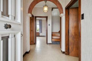 Deze charmante woning gelegen in Tielt biedt een totale bewoonbare oppervlakte van maar liefst 242 m² op een royaal perceel van 661 m². Ideaal voor gezinnen, beschikt dit huis over vier ruime slaapkamers en een badkamer. Bij het betreden van de woning wordt u verwelkomd in een royale hal met stijlvolle boogdetails, die verder leidt naar een lichte en luchtige woonkamer. De grote ramen zorgen voor een aangename lichtinval en bieden een prachtig uitzicht op de omgeving. De marmeren schouwmantels geven de ruimte een klassieke toets. De woning heeft een keuken die ingericht kan worden naar eigen smaak. De aansluitende zonnige veranda biedt een perfecte plek om te ontspannen met zicht op de tuin. Extra troeven van deze woning zijn de ruime garage en de bijkeuken, die extra opslag- en werkruimte bieden. De villa heeft een groot terras en een mooie tuin. Deze eigendom, biedt uitstekende toegang tot lokale voorzieningen, scholen en transportverbindingen. Met haar karaktervolle elementen en uitgebreide ruimtepotentieel is deze woning een uitstekende gelegenheid voor gezinnen die op zoek zijn naar een gezellig en functioneel huis in het hart van Tielt.