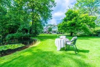 <p><strong>Karaktervol landhuis met prachtig aangelegde tuin, bijgebouw en extra naastliggend bouwperceel van ca 2077m² met verweven tuin optioneel bij aan te kopen – uniek woonaanbod op toplocatie</strong></p>
<p>In een residentiële en rustige omgeving wacht dit uitzonderlijk goed onderhouden landhuis op haar nieuwe bewoners. Gelegen op een royaal dubbel perceel met een schitterend aangelegde en volgroeide tuin, biedt deze eigendom een unieke combinatie van charme, ruimte en veelzijdigheid.<br /><strong>Bovendien geniet u van een uitstekende bereikbaarheid: op slechts 25 minuten rijden van zowel Eindhoven (NL) als Antwerpen (BE)</strong> – een ideale ligging voor wie centraal, maar toch in alle rust wil wonen.</p>
<p>Via de ruime inkomhal met gastentoilet en aparte bureauruimte betreedt u de sfeervolle leefruimte. De gezellige open haard, de brede raampartijen en de naadloze overgang naar de eetkamer zorgen voor een warme, huiselijke sfeer met overal zicht op de prachtige tuin. De volledig uitgeruste keuken is aangenaam ruim en beschikt over een aansluitende berging.</p>
<p>Op de eerste verdieping bevinden zich vier volwaardige slaapkamers en drie badkamers. De masterbedroom beschikt over een eigen inloopdressing, een royale badkamer én een privé-sauna – een ware wellnessbeleving aan huis.</p>
<p>Een bijzonder pluspunt is het multifunctionele bijgebouw, dat bestaat uit een ruime garage met drie poorten en meer dan voldoende opbergruimte. De bovenverdieping van dit gebouw is ingericht als hobbyruimte met een gezellige bar, douche en apart toilet – ideaal als gastenverblijf, atelier, of als zelfstandige ruimte voor inwonende tieners of hulp. Deze verdieping is bereikbaar via een aparte buitentrap.</p>
<p>De tuin is werkelijk een parel: aangelegd als een rustgevend park met vijvers, wandelpaadjes en idyllische zithoekjes vormt het geheel een oase van groen en stilte. Dit extra perceel biedt tevens potentieel voor wie toekomstgericht denkt aan bouwen of uitbreiden. Voor meer informatie over de villa met inbegrip van het optionele perceel verwijzen we u door naar onze eigen website.</p>
<p><strong>Kortom: een unieke kans voor wie op zoek is naar een karaktervol landhuis met veel ruimte, privacy, uitstekende bereikbaarheid en een uitzonderlijk mooie buitenomgeving.</strong></p>