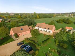<p><span>BOECHOUT/VREMDE</span><span>: Uniek domein bestaande uit hoeve, schuur en stallen</span></p><p><span>In het hart van het landelijke Vremde ontvouwt zich achter een uitgestrekt perceel van circa 19.000 m² een eigendom dat zelden zijn gelijke kent. </span></p><p><span>Dit landgoed biedt niet alleen ruimte, maar ook een levensstijl waarin rust, architectuur en natuur elkaar versterken.</span></p><p><span>Het domein bestaat uit drie afzonderlijke gebouwen die samen één krachtig geheel vormen. De voormalige hoeve werd grondig vernieuwd en uitgebreid, met respect voor het verleden en oog voor hedendaags comfort. Authentieke balken en karaktervolle materialen gaan er hand in hand met grote raampartijen en een open, lichtrijk interieur.</span></p><p><span>Op het gelijkvloers vindt u onder meer een ruime leefkeuken, praktische wasplaats, apart toilet, bureau, een royale leefruimte en een sfeervolle wijnkelder. </span></p><p><span>De verdieping herbergt een aparte studio met slaapkamer en badkamer, beide met uitzicht op het omliggende groen. Daarnaast zijn er nog twee bijkomende slaapkamers, een douche, dressing, sauna en een extra toilet.</span></p><p><span>Wat vandaag als schuur wordt omschreven, is in werkelijkheid een indrukwekkende multifunctionele ruimte met eigen keuken. Perfect als atelier, tentoonstellingsruimte, privéverzameling of inspirerende plek voor workshops en coachings. Het charmante voormalige bakkershuisje beschikt over twee slaapkamers en een badkamer, ideaal als gastenverblijf, kangoeroewoning of rustige werkplek.</span></p><p><span>Verder beschikt het domein over een recent gebouwd, hoogwaardig stallencomplex met piste. De biologische moestuin, omringd door fruitbomen en bloemen, maakt het plaatje compleet voor wie bewust en groen wil leven. Overname van de inboedel is bespreekbaar.</span></p><p><span>Een eigendom met eindeloze mogelijkheden en uitstraling komt maar zelden beschikbaar een unieke kans voor wie op zoek is naar een buitengewone woon- en belevingsplek.</span></p><p><span> </span></p><p><span>BIJZONDERHEDEN:</span></p><p><span> </span></p><p><span>- Rustige ligging te midden de natuur, omgeven door groen en uitgestrekte velden</span></p><p><span>- De eigendommen werden volledig gerenoveerd en verkeren in perfecte toestand</span></p><p><span>- Multifunctioneel en geschikt voor meerdere doeleinden</span></p><p><span> </span></p>