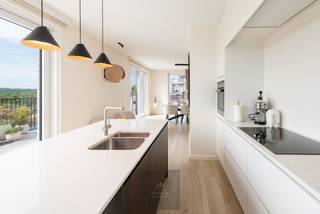 Appartement penthouse récent et luxueusement fini de 180 m², situé dans un emplacement de choix absolu avec des vues panoramiques sur les dunes protégées de Houtsaeger. Cette propriété exceptionnelle combine un agencement réfléchi avec des matériaux durables de haute qualité et une orientation écologique rare. Doté de trois chambres spacieuses et de deux salles de bains, l'appartement offre une expérience de vie unique grâce à ses grandes terrasses orientées vers le soleil, où vous pourrez profiter du calme et de la nature tout au long de la journée.<br />L'espace de vie lumineux avec cuisine ouverte s'intègre parfaitement à la terrasse et constitue le cœur battant de cette propriété. Grâce au chauffage par le sol et aux brise-soleil à commande électrique, le climat intérieur est toujours agréable. L'appartement est équipé d'une pompe à chaleur, d'un système de ventilation de type D et de pas moins de 24 panneaux solaires privés, ce qui contribue à sa neutralité énergétique. La récupération d'eau de pluie de 8000 litres avec un système d'arrosage automatique pour les jardinières intégrées souligne le caractère écologique de cette propriété unique.<br />La chambre principale dispose d'une salle de bains attenante avec baignoire, douche à l'italienne et double lavabo. Il y a également une deuxième salle de bains avec douche à l'italienne et des toilettes supplémentaires, ainsi qu'un local technique pratique avec une buanderie. Des détecteurs de mouvement assurent l'éclairage automatique des toilettes, du hall de nuit, du local technique, du sous-sol et du garage, entre autres. Grâce à son agencement intelligent et à son double espace de vie, ce penthouse offre également des possibilités en tant que maison kangourou ou pour les professionnels à la recherche d'une combinaison confortable de vie et de travail. Un grand garage souterrain avec station de recharge électrique peut être acheté en option. L'emplacement est idéal : à proximité du célèbre club de sports nautiques KYC et à quelques pas des hauts lieux culinaires et des boutiques de Sint-Idesbald. Une opportunité exceptionnelle pour ceux qui recherchent l'espace, le confort, la nature et la durabilité dans un emplacement de choix au bord de la mer. EPC : -4 kWh/m². Prix demandé : 1135000€.