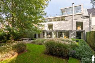 <p><strong>Exclusieve architectenwoning met panoramisch zicht op natuurgebied<br /></strong>Aan de rand van Park Callebeek-Terlocht, met toegang vanuit de eigen tuin, bevindt zich deze bijzondere architectenwoning. Qua ligging en bereikbaarheid in de onmiddellijk nabijheid van de waterbus, welke rechtstreeks en file-vrij een unieke regelmatige verbinding geeft met het centrum van Antwerpen.<br /><br />Met <strong>ca. 570 m² bew. opp.,</strong> een doordachte indeling en een sterke architecturale uitstraling combineert de woning comfortabel wonen met de mogelijkheid om een professionele activiteit uit te oefenen. Hoge plafonds, grote glaspartijen, maatwerk en zorgvuldig gekozen materialen bepalen het karakter. Het ontwerp verscheen bovendien in verschillende architectuur- en interieurpublicaties.<br /><br /><strong>Wonen met zicht op groen<br /></strong>Via de ruime inkomhal met <strong>lift</strong> bereikt u de leefruimte met vide. De hoge plafonds en grote raampartijen zorgen voor veel licht en een open zicht op de tuin. Een sfeervolle haard brengt warmte in het strakke interieur.<br /><br />De aansluitende maatwerkkeuken beschikt over een groot kookeiland, hoogwaardige toestellen en een geïntegreerde eetruimte. Donkere houtaccenten en lichte materialen vormen er een stijlvol geheel.<br /><br />Op het GLVL bevinden zich verder een bijkeuken/wasplaats, een multifunctionele ruimte die ook als logeerkamer kan dienen, met douchevoorziening, en een dubbele inpandige garage.<br /><br /><strong>Rust en privacy op de eerste verdieping<br /></strong>De 1eV herbergt een royale master suite met dressing en luxueuze badkamer, inclusief hamam. Daarnaast bevindt zich een bijzonder ruime tweede slaapkamer met eigen douchekamer, eventueel op te delen in twee afzonderlijke slaapkamers.<br /><br />Een <strong>open home office</strong> met zicht op de onderliggende leefruimte en de groene omgeving vervolledigt deze verdieping.<br /><br /><strong>Een veelzijdige tweede verdieping<br /></strong>De 2eV, met een opp. van ca. 140 m², is ingericht als<strong> professionele kantoorruimte </strong>en biedt uitzonderlijke mogelijkheden.<br /><br />De oorspronkelijke stedenbouwkundige vergunning voorziet in een combinatie van wonen en een praktijk voor een vrij beroep. Dit maakt de woning interessant voor wie wonen en werken op een stijlvolle manier wil verenigen. Ook andere invullingen als creatieve studio of bijkomende privéruimte (kangoeroewonen) bieden perspectieven, onder voorbehoud van de geldende voorschriften.<br /><br />Absolute blikvanger is het <strong>royale terras van ca. 47 m²</strong>, met een adembenemend uitzicht over het aangrenzende natuurgebied.<br /><br />Een volledig beglaasde panoramaruimte op het hoogste niveau vormt de architecturale bekroning van deze residentie.<br /><br /><strong>Een tuin die aansluit op het landschap<br /></strong>De aangelegde tuin met siergrassen, volwassen bomen en strakke lijnen vormt een rustig verlengde van de woning. Via de tuin heeft u rechtstreeks toegang tot het achterliggende park: een bijzondere meerwaarde voor wie graag midden in het groen woont.<br /><br /><strong>Comfort en techniek<br /></strong>De lift verbindt de kelder met de 2eV. Verder beschikt de woning over zonnepanelen, zonnecollectoren, airco, automatische zonwering, uitgebreide veiligheidsvoorzieningen en talrijke ingemaakte kasten. De ruime kelder biedt plaats voor opslag, archief of een wijncollectie.<br /><br /><strong>Bijzondere troeven:</strong></p>
<ul>
<li>Ca. 570 m² bew. opp.</li>
<li>Rechtstreekse toegang tot Park Callebeek-Terlocht</li>
<li>Lichtrijke leefruimte met vide</li>
<li>Master suite met dressing</li>
<li>2eV van ca. 140 m² met veel mogelijkheden, bereikbaar met lift</li>
<li>Panoramisch terras van ca. 47 m²</li>
<li>Dubbele garage en extra parkeergelegenheid</li>
<li>EPC B – 123 kWh/m²</li>
<li>Zonnepanelen, zonnecollectoren en warmtepompen</li>
<li>Veel ingemaakte kasten en automatische zonwering</li>
</ul>