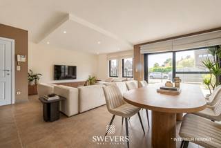Voor meer info en foto’s, surf naar www.swevers.be – Dit instapklare gelijkvloerse appartement in het centrum van Zolder combineert een ruime indeling met aangenaam wooncomfort. Met een bewoonbare oppervlakte van 120 m², drie slaapkamers en een privatieve tuin rondom is dit een ideale woning voor wie comfortabel en gelijkvloers wil wonen. Het appartement maakt deel uit van een verzorgd gebouw uit 2007 en beschikt bovendien over een ondergrondse autostaanplaats en een kelderberging. Via de inkomhal bereikt u de ruime leefruimte van bijna 52 m², waar woonkamer en eetkamer naadloos in elkaar overvloeien. Dankzij de royale oppervlakte geniet u hier van alle vrijheid om een gezellige zithoek en een volwaardige eethoek in te richten. Aansluitend bevindt zich de praktische keuken met voldoende werk- en opbergruimte. De nachthal geeft toegang tot drie slaapkamers van respectievelijk 13,26 m², 9,51 m² en 9,07 m². Deze ruimtes zijn perfect inzetbaar als slaapkamer, bureau, hobbykamer of logeerkamer. De badkamer is uitgerust met zowel een bad als een douche. Daarnaast is er een aparte toiletruimte en een handige berging. Buiten geniet u van een tuin rondom het appartement, met een terras aan de voorzijde en een overdekt terras van 9,61 m² aan de achterzijde. De zuidwestgerichte achtertuin biedt volop zon in de namiddag en avond en vormt een aangename plek om tot rust te komen. Extra troeven zijn de zonnepanelen, rolluiken, parlofoon, lift en de vlotte verbinding tussen de ondergrondse parking en het appartement. Scholen, winkels, restaurants, openbaar vervoer en ontspanningsmogelijkheden bevinden zich op wandel- of korte rijafstand. Ook de snelwegen zijn snel bereikbaar. Voor meer informatie, bel 011 255 155. Bron bewoonbare oppervlakte: EPC – verslag.