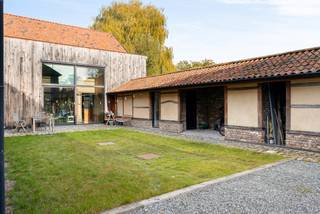 In het hart van het gegeerde Wimmertingen, op de Luikersteenweg 512, bevindt zich het uitzonderlijke en beschermd pand “Hoeve De Klok” – een uniek gesloten hoevecomplex dat authenticiteit en hedendaags comfort op sublieme wijze combineert.<br />Aan de straatzijde bevindt zich het statige poortgebouw met een ruim te renoveren woonhuis, ideaal als toekomstig kantoor, praktijk of woongedeelte. Dankzij de centrale ligging, de uitstekende bereikbaarheid en de nabijheid van een ruime parking is dit een uitgelezen locatie voor wie wonen en werken wil combineren. Voor dit gedeelte is bovendien een apart huisnummer mogelijk.<br />Georiënteerd op de ruime tuin vind je de voormalige vakwerkschuren, die met veel zorg voor detail en respect voor het erfgoed werden omgevormd tot een moderne, instapklare woning. <br />De renovatie gebeurde met oog voor energie-efficiëntie en comfort, waarbij hedendaagse technieken en hoogwaardige materialen werden geïntegreerd zonder afbreuk te doen aan het authentieke karakter van het gebouw.<br />De woning beschikt over vloerverwarming in combinatie met een lucht-water warmtepomp, een ventilatiesysteem type C en een geavanceerd domoticasysteem. Daarnaast werd er gedacht aan modern wooncomfort met een laadpaal voor elektrische wagens, automatische screens aan de voorgevel, en een gezellige houthaard als sfeervol middelpunt van de leefruimte.<br />Verder is het pand uitgerust met regenwaterrecuperatie, en een centraal audiosysteem dat in de hele woning geïntegreerd is. De volledig uitgeruste keuken met kwalitatieve inbouwtoestellen vervolledigt het geheel en maakt deze woning meteen instapklaar voor wie comfort en authenticiteit wil combineren.<br />De bovenverdieping telt momenteel 2 ruime slaapkamers, maar kan eenvoudig worden uitgebreid of heringedeeld volgens eigen wensen. De slimme inrichting met lichttracks, programmeerbare verlichting, onzichtbare vloerkanalen en talrijke data-aansluitpunten maakt dit pand bijzonder polyvalent.<br />De gebouwen zijn gegroepeerd rond een sfeervolle zuidwestgerichte binnenruimte die door de ommuring een aangenaam microklimaat creëert – ideaal voor een intiem terras of binnentuin. Daarachter strekt zich een ruime, rustige tuin uit die aansluit op een natuurgebied: een perfecte plek om tot rust te komen of om te vertrekken voor ontspannende wandelingen in het groen. Bron bewoonbare oppervlakte: EPC.<br /><br />Buitengewone kenmerken: <br />- Vloerverwarming<br />- Lucht-water warmtepomp<br />- Ventilatiesysteem type C<br />- Domoticasysteem<br />- Laadpaal<br />- Automatische screens aan de voorgevel<br />- Branddetectiesysteem met voorbereiding inbraakdetectie<br />- Centraal audiosysteem<br />- Te renoveren extra woning +- 200m2