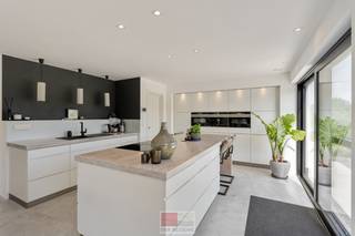Wonen waar elke dag als vakantie voelt<br /><br />Sommige woningen bieden comfort. Andere bieden ruimte. En dan zijn er plekken waar alles samenkomt: hedendaags wonen, rust en een uitzicht dat je niet snel vergeet.<br />Op een royaal perceel van circa 910 m² ligt deze moderne en energiezuinige woning van circa 177 m² bewoonbare oppervlakte, met een weids panorama over het Limburgse Heuvelland. <br /><br />De open leefkeuken en de aangrenzende eetruimte vormen het hart van het huis. Via schuifpuien loopt de leefruimte direct over in het terras en de tuin, waardoor binnen en buiten op een natuurlijke manier in elkaar overvloeien. Op de bovenverdieping bevinden zich drie kamers, twee badkamers en een separaat toilet. De ruime mastersuite beschikt over een eigen badkamer en walk-in closet. Daarnaast is er een tweede slaapkamer en een derde kamer die momenteel ingericht is als tv- en ontspanningsruimte, maar eenvoudig kan worden omgevormd tot volwaardige derde slaapkamer.<br /><br />Ook op het gebied van techniek is aan alles gedacht. De geothermische warmtepomp, vloerverwarming en passieve koeling zorgen het hele jaar door voor een aangenaam binnenklimaat. De zonnepanelen dragen bij aan een energiezuinige werking, terwijl de automatische toegangspoort, slimme verlichting en camerabeveiliging extra gemak en privacy bieden. Buiten wordt het vakantiegevoel compleet. De mediterrane beplanting, verschillende terrassen, de fraai aangelegde zwemvijver en vooral het unieke, weidse uitzicht over het glooiende landschap maken dit een plek waar je iedere dag opnieuw tot rust komt. <br /><br />En misschien is dat precies wat deze woning zo bijzonder maakt. Je hoeft niet ver te reizen om er even helemaal uit te zijn. <br /><br />Modern wonen. Eindeloos uitzicht. Elke dag een beetje vakantie.<br /><br />Teuven – wonen midden in het Heuvelland<br /><br />De woning bevindt zich in het pittoreske Teuven, een karaktervol dorp in de gemeente Voeren, midden in het prachtige landschap van de Voerstreek. De omgeving wordt gekenmerkt door glooiende heuvels, uitgestrekte weilanden, bossen en de vallei van de Gulp en vormt daarmee een bijzondere woonomgeving voor liefhebbers van rust, natuur, wandelen en fietsen.<br />Teuven beschikt over een charmante dorpskern met de historische Sint-Pieterskerk als herkenningspunt en een verrassend levendig horeca-aanbod. Vanuit het dorp vertrekken talrijke wandel- en fietsroutes door het heuvelachtige landschap en de omliggende Voerense bossen.<br />Ondanks de landelijke ligging zijn verschillende voorzieningen en omliggende dorpen vlot bereikbaar. Ook de nabijheid van de Nederlandse grens is een belangrijke troef. Slenaken, Aubel en ’s-Gravenvoeren liggen op korte afstand, terwijl ook Maastricht, Luik en Aken goed bereikbaar zijn.<br />Een omgeving die uitblinkt in rust, groen, ruimte en landelijke charme, maar tegelijkertijd uitstekend verbonden blijft met de omliggende dorpen en steden.<br /><br />Bezichtig deze woning ook digitaal en 'loop' zelf door de woning. Kijk daarvoor op onze website of via: my.matterport.com/show/?m=D3ATBZQCmxw<br /><br />INDELING<br /><br />Gelijkvloers:<br /><br />- Inkomhal met vestiaire kasten;<br />- Gastentoilet met lavabo met onderkast;<br />- Betonnen trap (kan desgewenst naar smaak verder worden afgewerkt);<br />- Ruime living met directe toegang tot de eetkamer en keuken;<br />- Eetkamer met zicht op de prachtig aangelegde tuin;<br />- Complete keuken met allemaal Siemens toestellen (vaatwasser, combi-oven, inbouwkoffiezet, oven, XXL frigo, Novy inductieplaat met ingebouwde dampkap), afgietbak (Franke) op apart kastengedeelte, groot eiland met 4 zitplaatsen, twee grote schuifpuien met vliegenhor;<br />- Leefkamer voorzien van sierhaard (op Bio-ethanol); kan desgewenst zonder ingrijpende werken worden verwijderd;<br />- Berging die toegang verschaft tot de zijdeur.<br /><br />1e verdieping: <br /><br />- Slaapkamer 1, momenteel ingericht als kantoor;<br /><br />- Slaapkamer 2, momenteel ingericht als ontspanningsruimte (met minimale ingrepen om te vormen naar slaapkamer);<br />- Masterbedroom met achterliggende doorloopdressing en prachtig vrijstaand bad met zicht op het heuvelland, grote wastafel met 2 natuurstenen wasbakken en inbouwkranen, inloopdouche met inbouwkranen, sfeerverlichting, slimme stopcontacten bij het bed-hoofdeinde zorgen voor extra comfort;<br />- Apart toilet;<br />- Aparte badkamer met enkel wasmeubel met natuurstenen wasbak, inloopdouche, slim geïntegreerde bergruimte met aansluiting voor wasmachine.<br /><br />Zolder:<br /><br />- Volledig geïsoleerde en geventileerde zolder met vlizotrap, ingericht als praktische bergzolder (mogelijks kan hier een extra leefruimte van worden gemaakt).<br /> <br />Tuin:<br /><br />- Oost georiënteerde tuin;<br />- Prachtig aangelegd terras rond het huis van 70m²;<br />- Hardhouten terras rond de zwemvijver;<br />- Volledig geautomatiseerde sierverlichting;<br />- Twee prachtige volwassen olijfbomen;<br />- Van voor tot achteraan de tuin meerdere waterpunten en voorzien van een irrigatiesysteem wat zorgt dat uw beplanting steeds voldoende water krijgen; <br />- Prachtige zwemvijver met filterkwaliteit 4 (d.w.z. dat de helderheid en properheid niet enkel afhangt van planten maar ook van meerdere mechanische filters wat zorgt voor optimale kwaliteit);<br />- Poort in aluminium, geïntegreerd pakjesluik en bel met codeklavier om toegang te krijgen via het toegangspoortje;<br />- Volledig voorzien van buitencamera's en buitenstopcontacten.<br /><br />Bijzonderheden:<br /><br />- Zeer gunstig EPC label;<br />- Geothermische warmtepomp van Vaillant; <br />- Vloerverwarming en passieve koeling op alle verdiepingen;<br />- Zonnepanelen (ZO gericht), 20 stuks met 327 WP/stuk;<br />- Ventilatiesysteem D met warmteterugwinning;<br />- Triple beglazing;<br />- Philips Hue verlichting;<br />- Regenwaterput 6000 liter (wasmachine, buitenkraan en toiletten zijn hierop aangesloten);<br />- Septische put aangesloten op riolering;<br />- Laadpaalvoorzieningen;<br />- Ruime kruipkelder onder de volledige woning.<br /><br />Energieprestatie en binnenklimaat (EPB-EPC)<br />Certificaat beschikbaar: ja<br />EPC certificaatnummer: 73109-G-2015_98/EP00869/A001/D01/SD001<br />Berekende energiescore : (kWh/m²): 53,14 kWh/m² jaar - A label<br />Het certificaat is geldig tot en met: 19-09-2027<br />Electrische installatie: ja - CONFORM<br /><br />Informatie stedenbouwkundige voorschriften:<br />Stedenbouwkundige vergunning: ja<br />Meest recente bestemming: landschappelijk waardevolle agrarische gebieden, woongebieden met landelijk<br />karakter<br />Dagvaarding uitgebracht: neen<br />VOORKOOPRECHT OP DIT GOED: neen<br />VERKAVELINGSVERGUNNING: neen<br />WATERGEVOELIG OPENRUIMTEGEBIED: neen<br />Maatregelenregister: ja - geen maatregelen<br /><br />Overstromingsgevoelige gebieden: <br />Perceelscore of P-score : A<br />Gebouwenscore of G-score: A<br />Ligging in Signaalgebied: neen<br />Ligging in afgebakende oeverzone of afgebakend overstromingsgebied: neen<br /><br />A:geen overstroming gemodelleerd B: kleine kans op overstromingen onder klimaatverandering C: kleine kans op overstromingen D: middelgrote kans op overstromingen<br /><br />Beschermd erfgoed<br />GEINVENTARISEERD ERFGOED: neen <br />BESCHERMD ONROEREND ERFGOED: neen