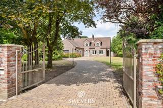 Voor meer info en foto’s, surf naar www.swevers.be – Ontdek deze instapklare open bebouwing aan de Laeremansstraat 21 in Koersel, gelegen op een uitzonderlijk perceel van 1 ha 35 a 73 ca met open zicht op agrarisch gebied. Hier geniet u van maximale privacy, rust en ruimte, terwijl winkels, scholen en andere voorzieningen vlot bereikbaar zijn. De villa, gebouwd in 1988, biedt 302 m² bewoonbare oppervlakte en is kwalitatief afgewerkt met onder meer parketvloeren. Op het gelijkvloers vindt u een ruime inkomhal met gastentoilet, een lichtrijke woonkamer met eetkamer, een volledig uitgeruste keuken met zicht op het overdekte terras, een praktische wasplaats, een slaapkamer en een inpandige dubbele garage. Op de verdieping bevinden zich nog twee ruime slaapkamers, waarvan één met een aparte dressing, twee badkamers en een berging. De royale kelder van ca. 120 m² biedt extra bergruimte en een bijkomende garage of opslagruimte. Dankzij de noordwestelijke oriëntatie geniet u volop van de avondzon. Het uitgestrekte terrein is ideaal voor dierenliefhebbers of het houden van paarden en biedt tal van mogelijkheden. Scholen liggen op 1,3 km, openbaar vervoer op 350 m, winkels en horeca op 2 km en de autosnelweg bereikt u in slechts 7 km. Een unieke eigendom voor wie op zoek is naar ruimte, comfort en een groene omgeving. Voor meer informatie, bel 011 255 155. Bron bewoonbare oppervlakte: EPC – verslag.